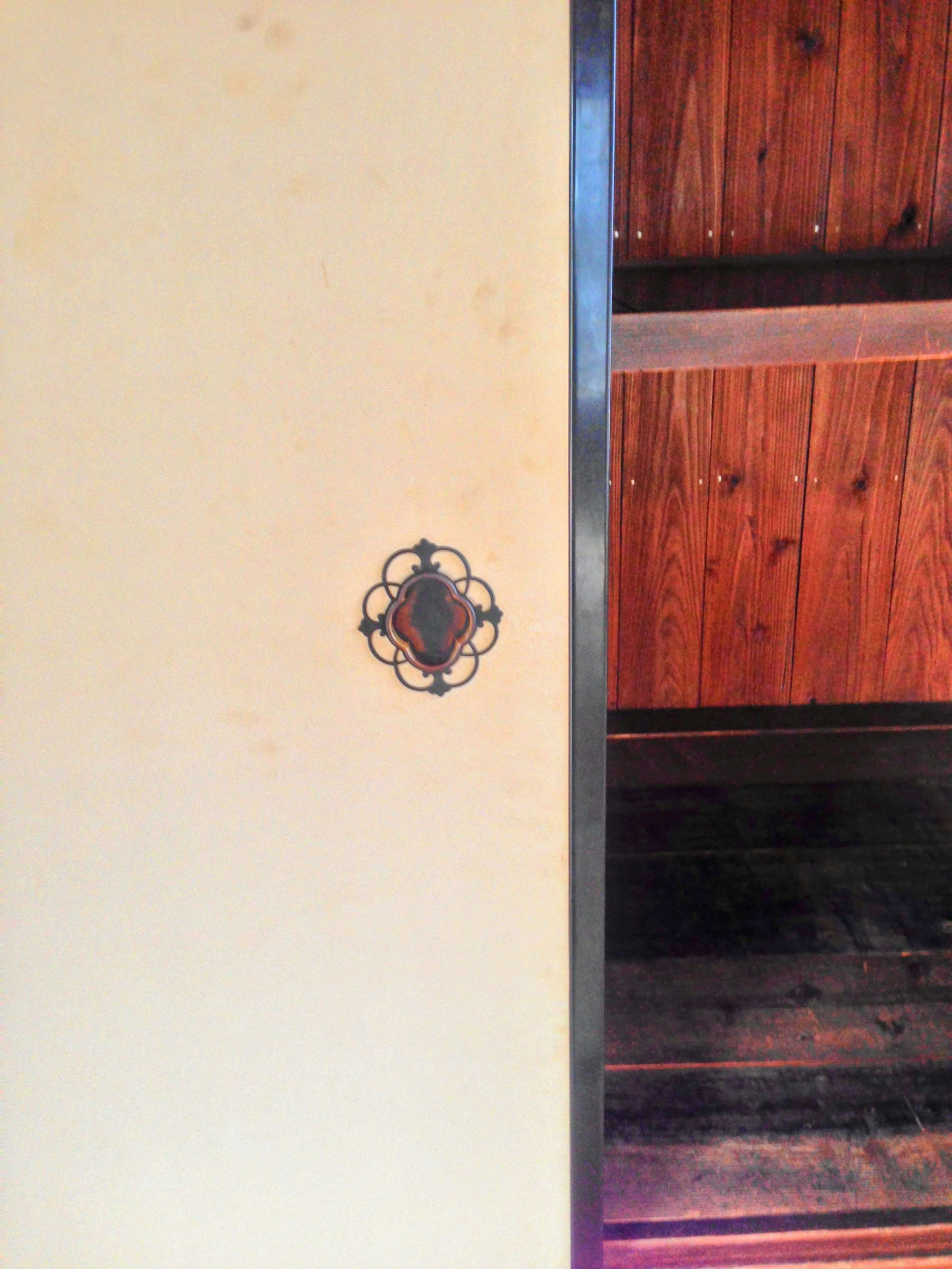 A section of a room featuring a door handle and wooden shelves