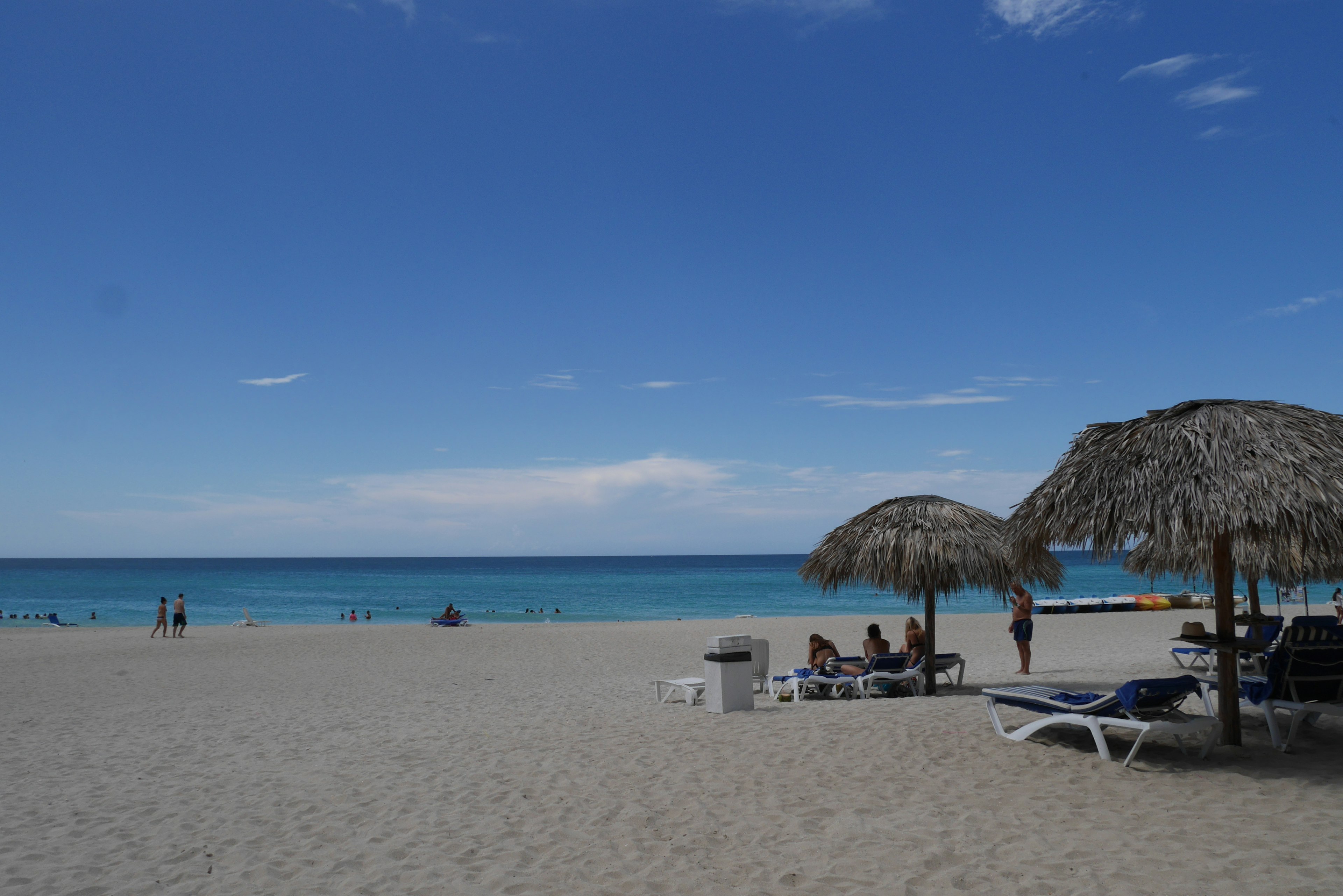 Escena de playa con océano azul arena blanca sombrillas y tumbonas