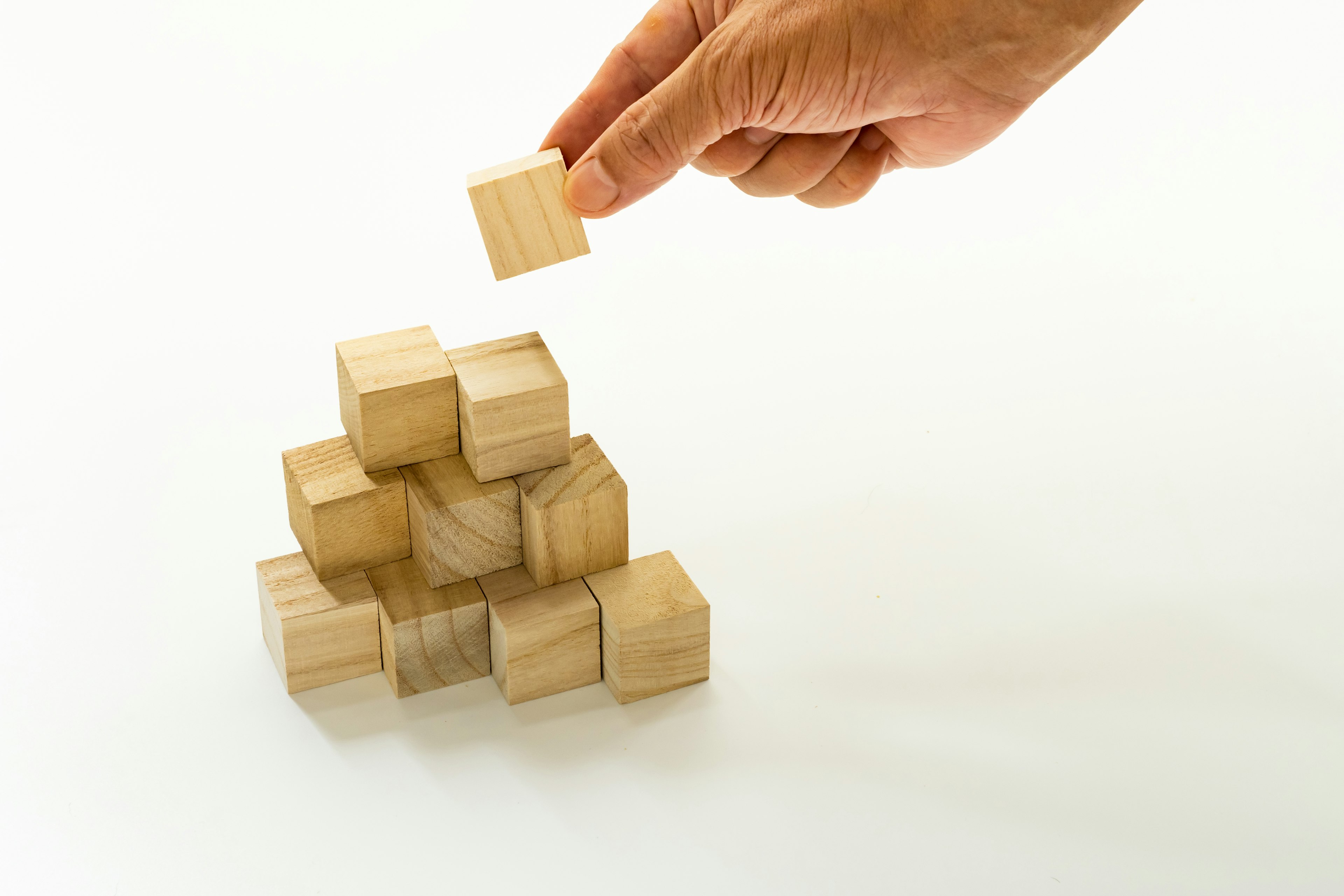 A hand placing a wooden block on a stack of wooden blocks