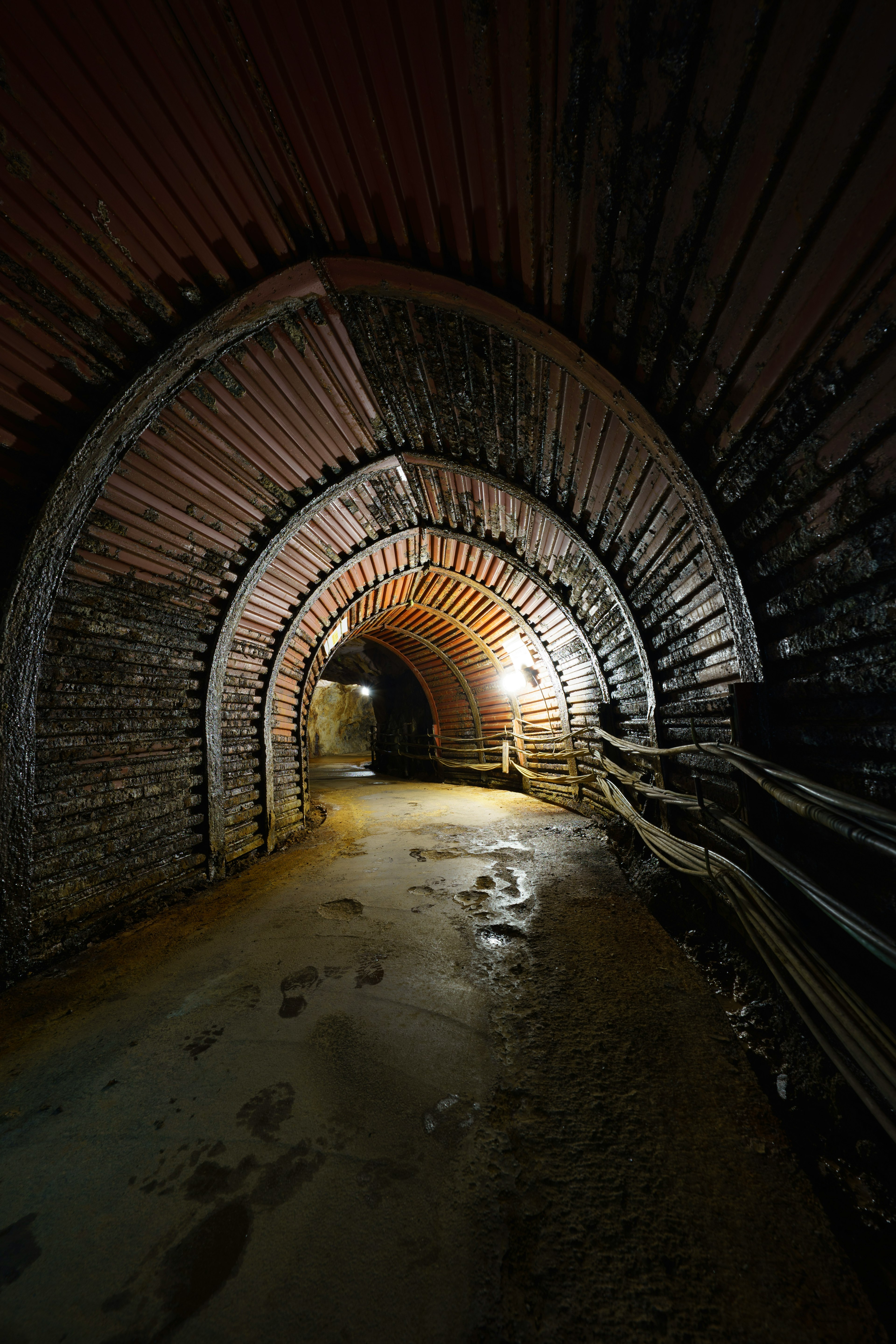 Vista interior de un túnel oscuro con estructura de ladrillos en arco y iluminación