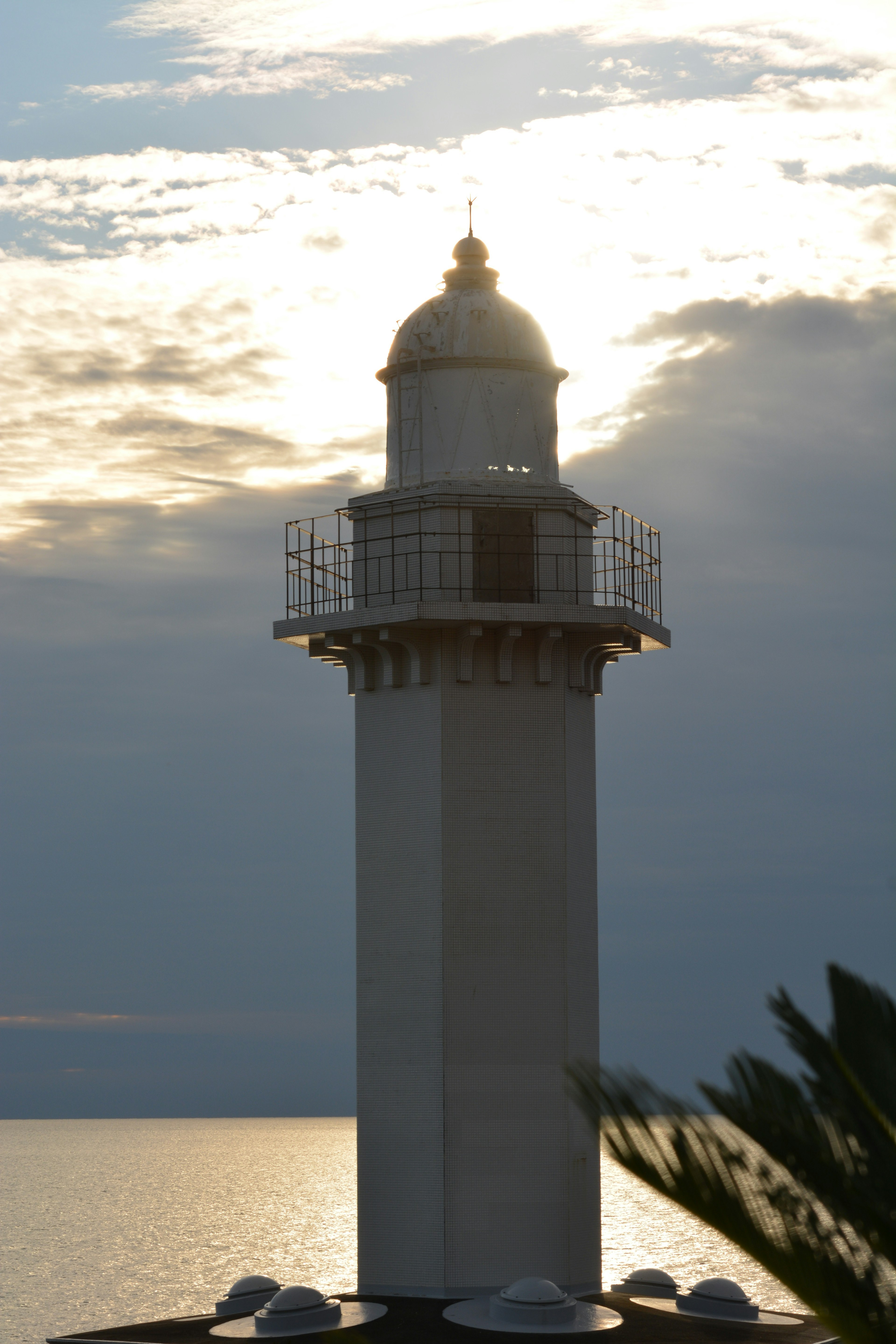 Lighthouse standing by the sea during sunset