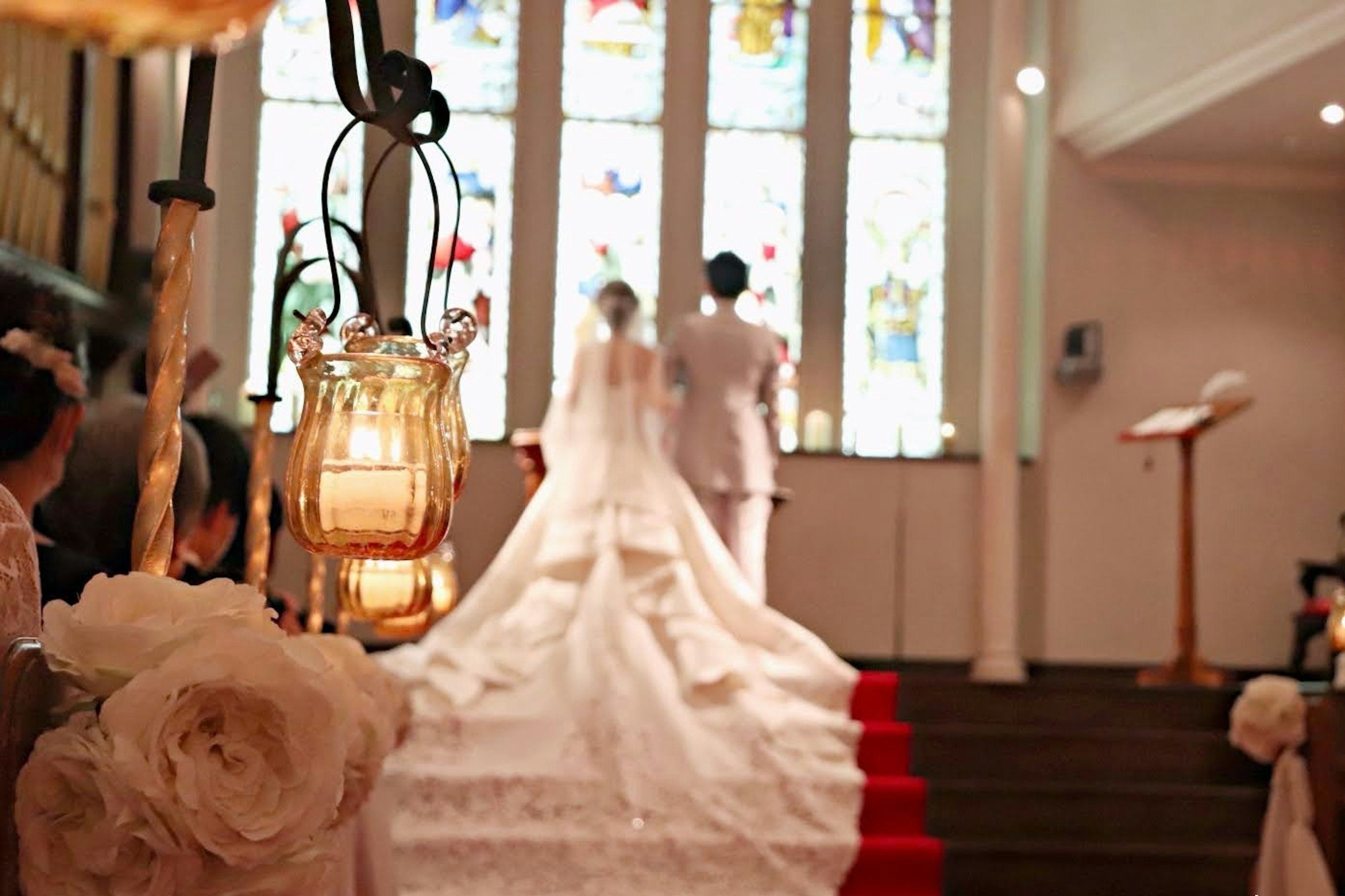 A wedding couple standing in front of stained glass in a church