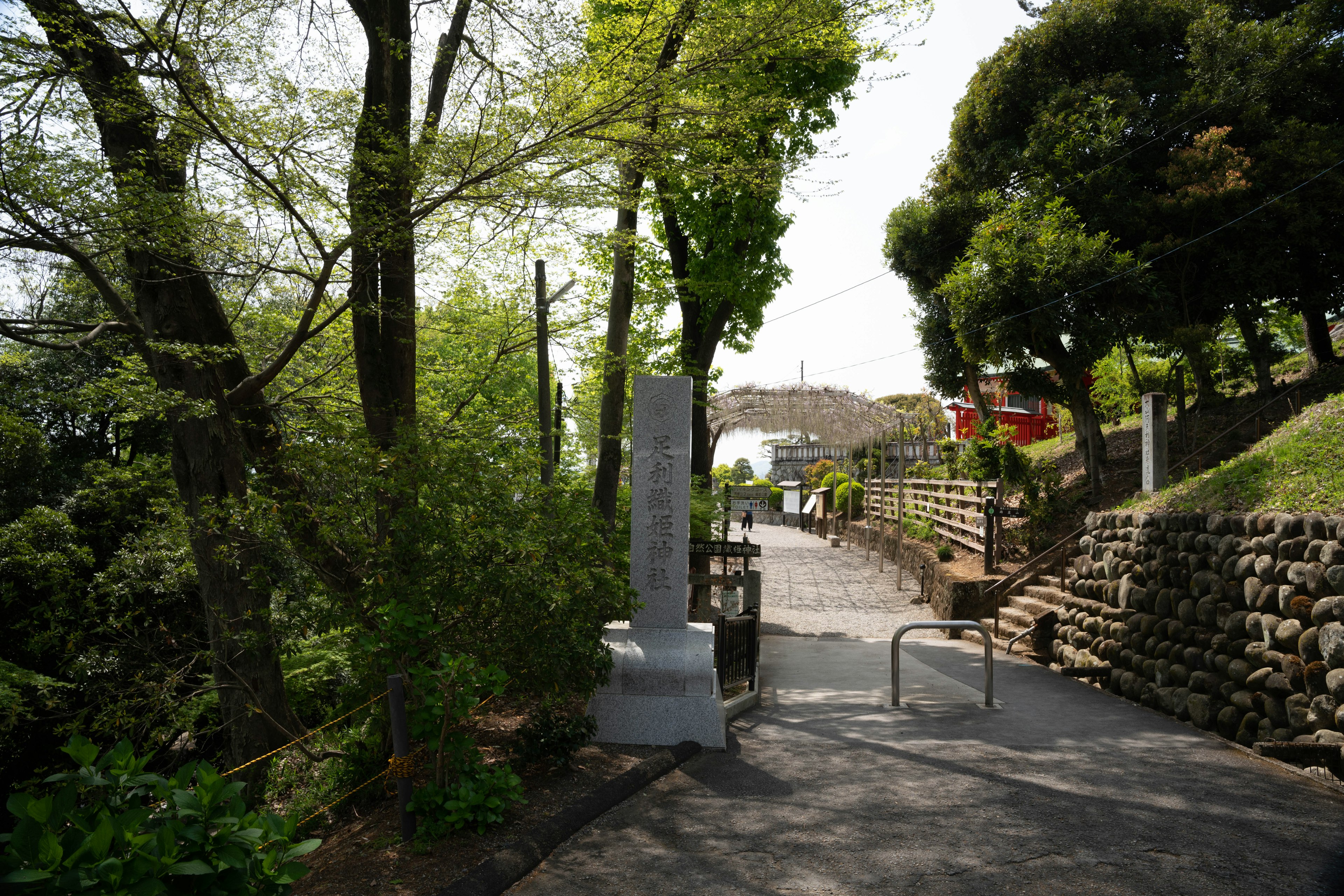 緑豊かな木々に囲まれた道と石のモニュメントが見える風景