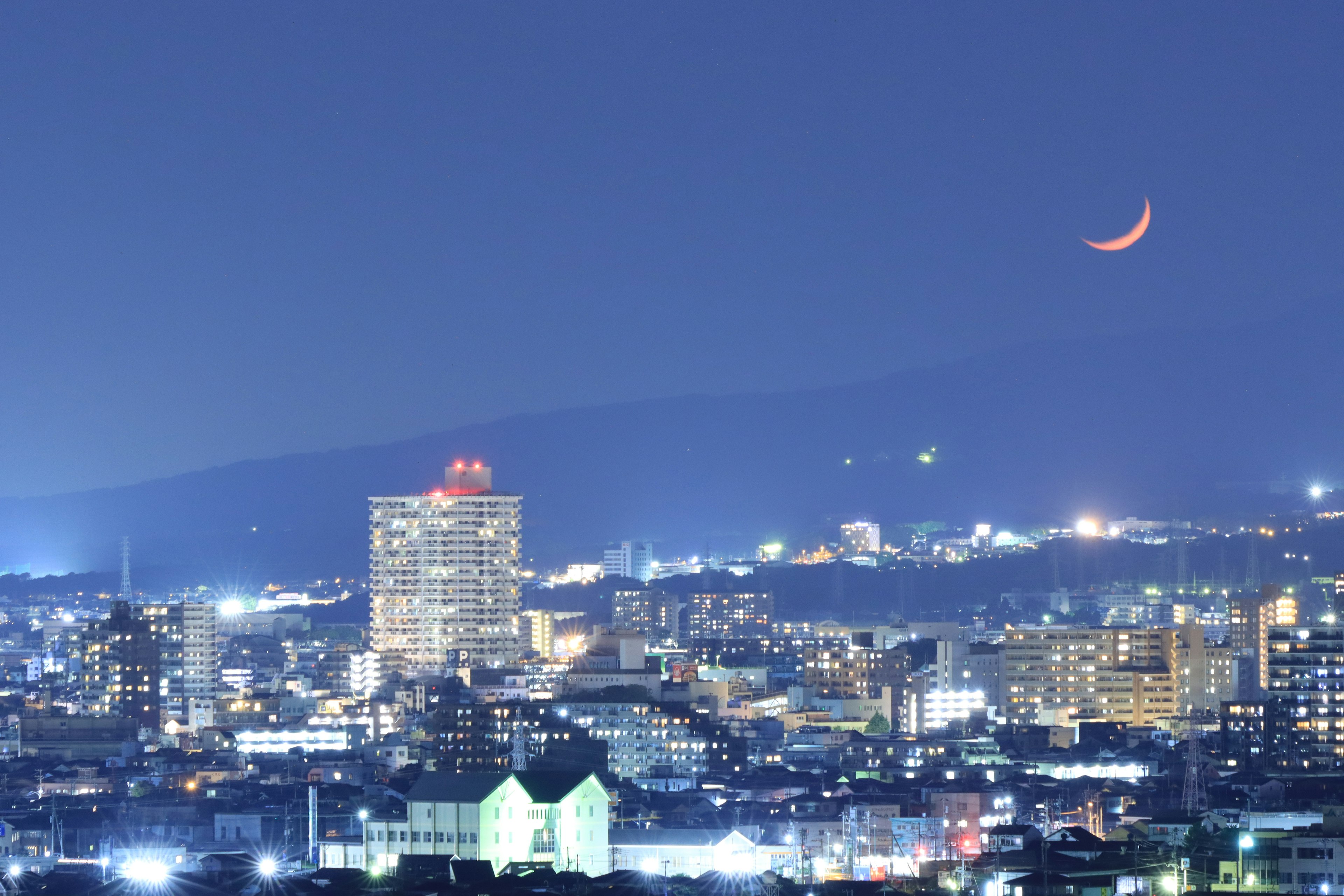 Beautiful cityscape at night with a crescent moon and illuminated buildings