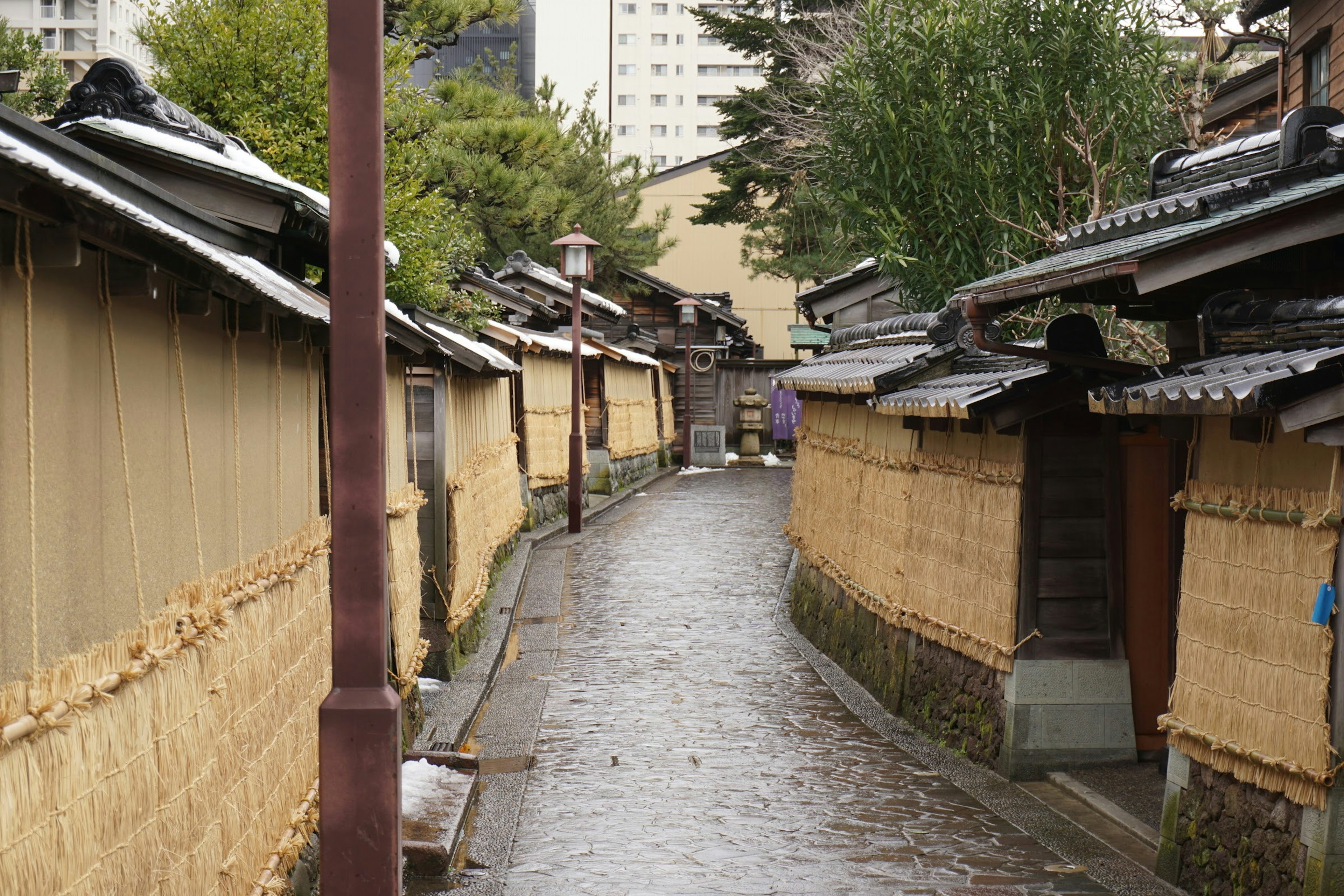 Enge steinerne Gasse mit traditionellen japanischen Häusern und Bambuszäunen