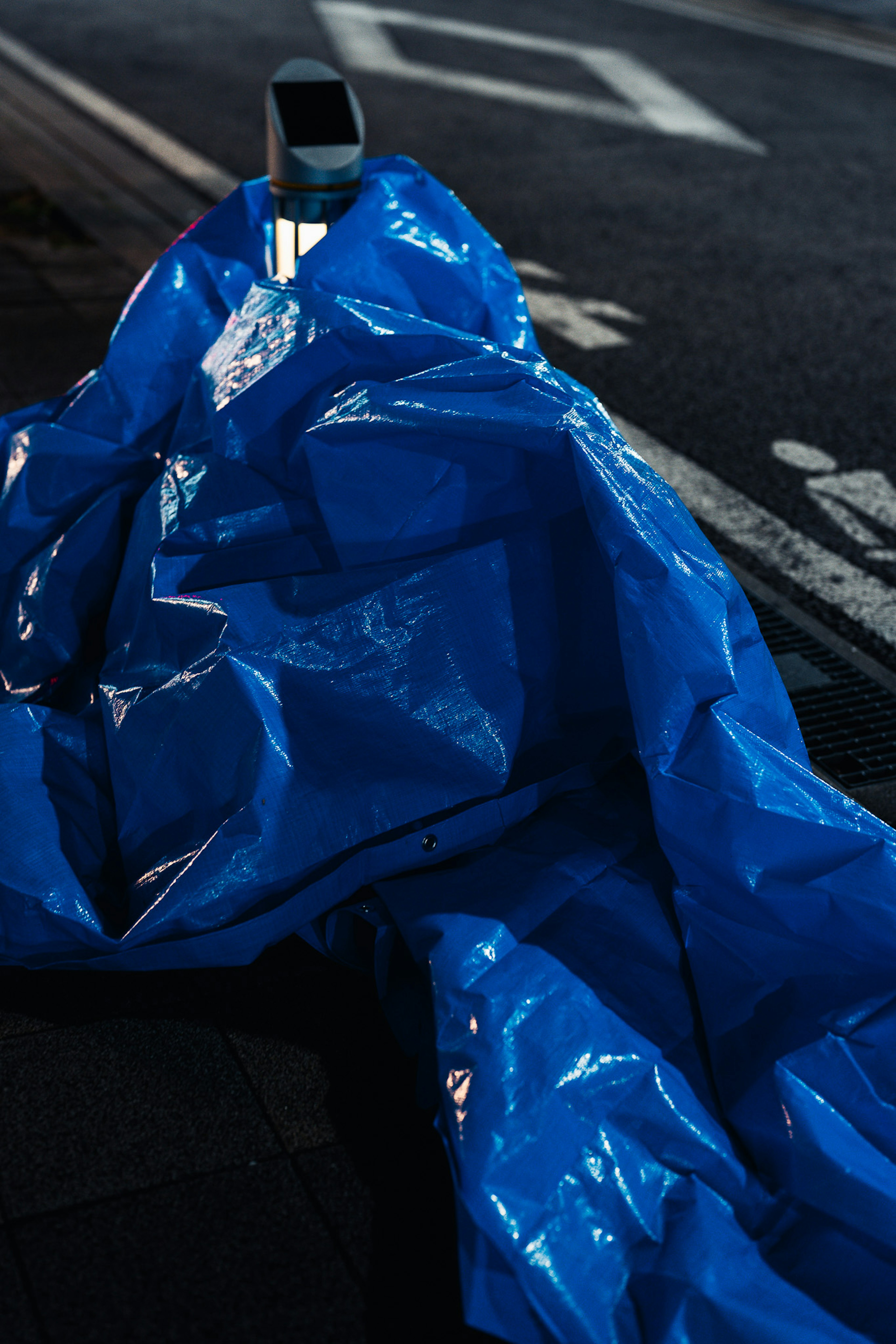 Una hoja de plástico azul extendida en la calle