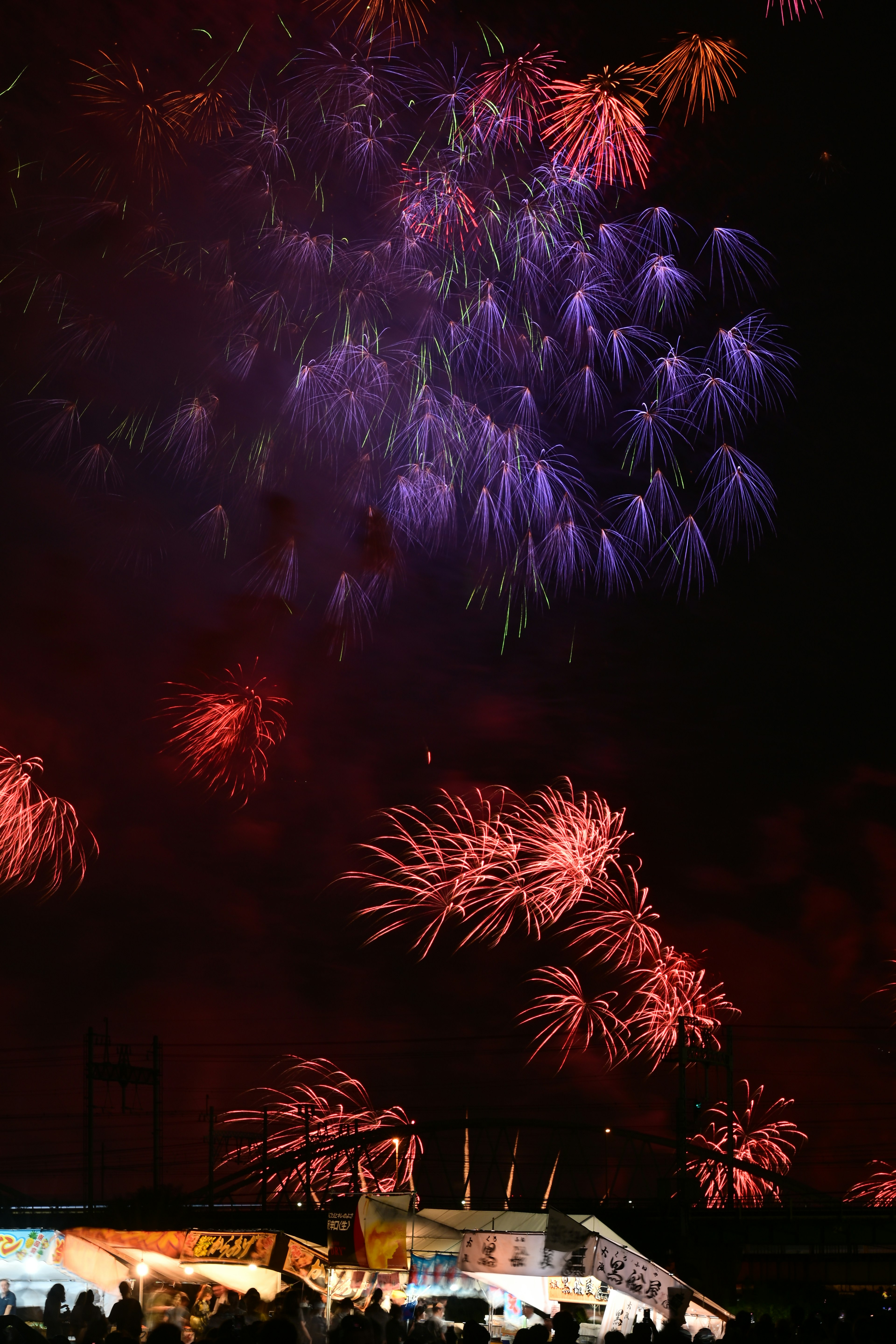 Colorful fireworks display in the night sky featuring purple and red bursts