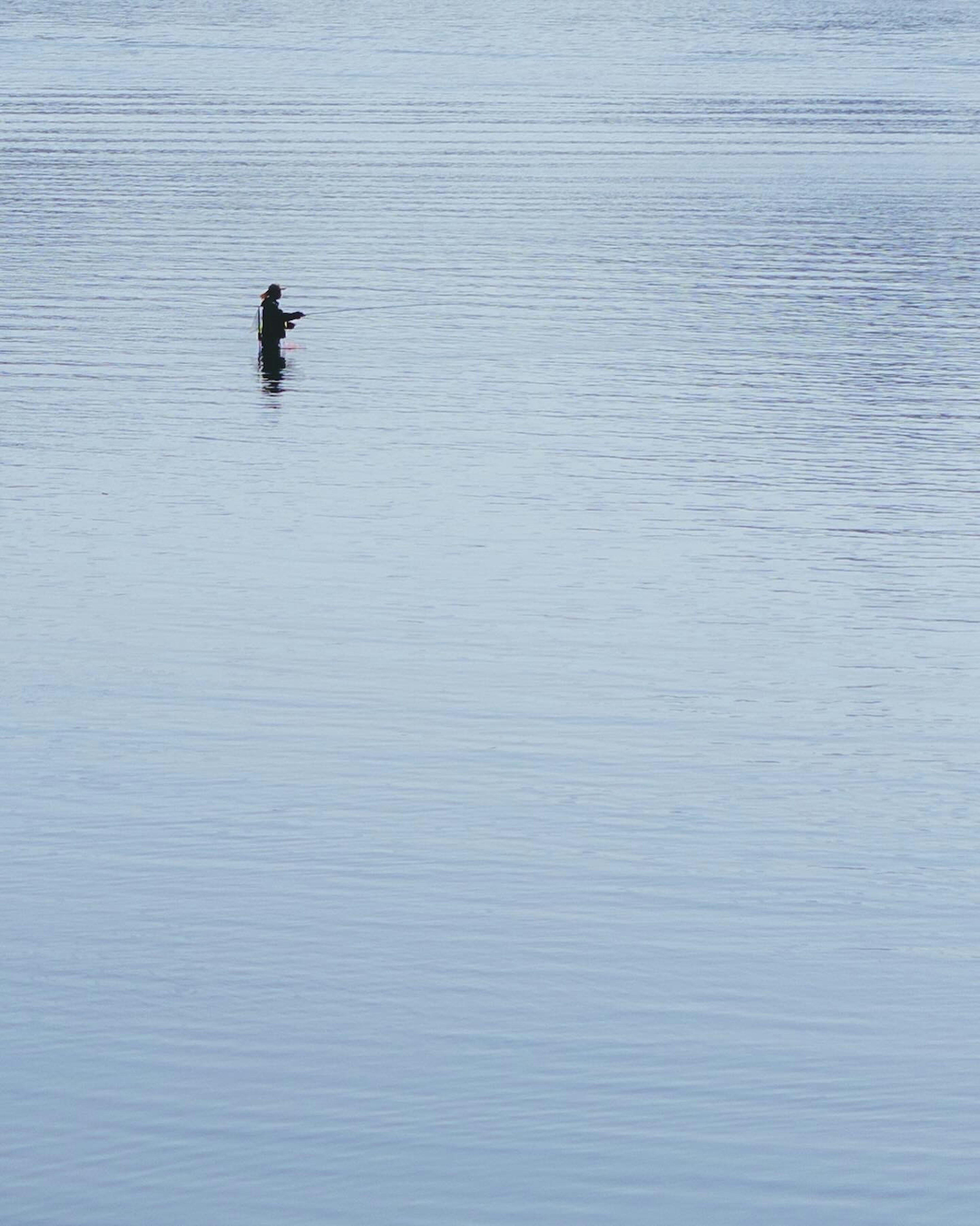 Une silhouette d'une personne debout sur la surface de l'eau dans un paysage serein