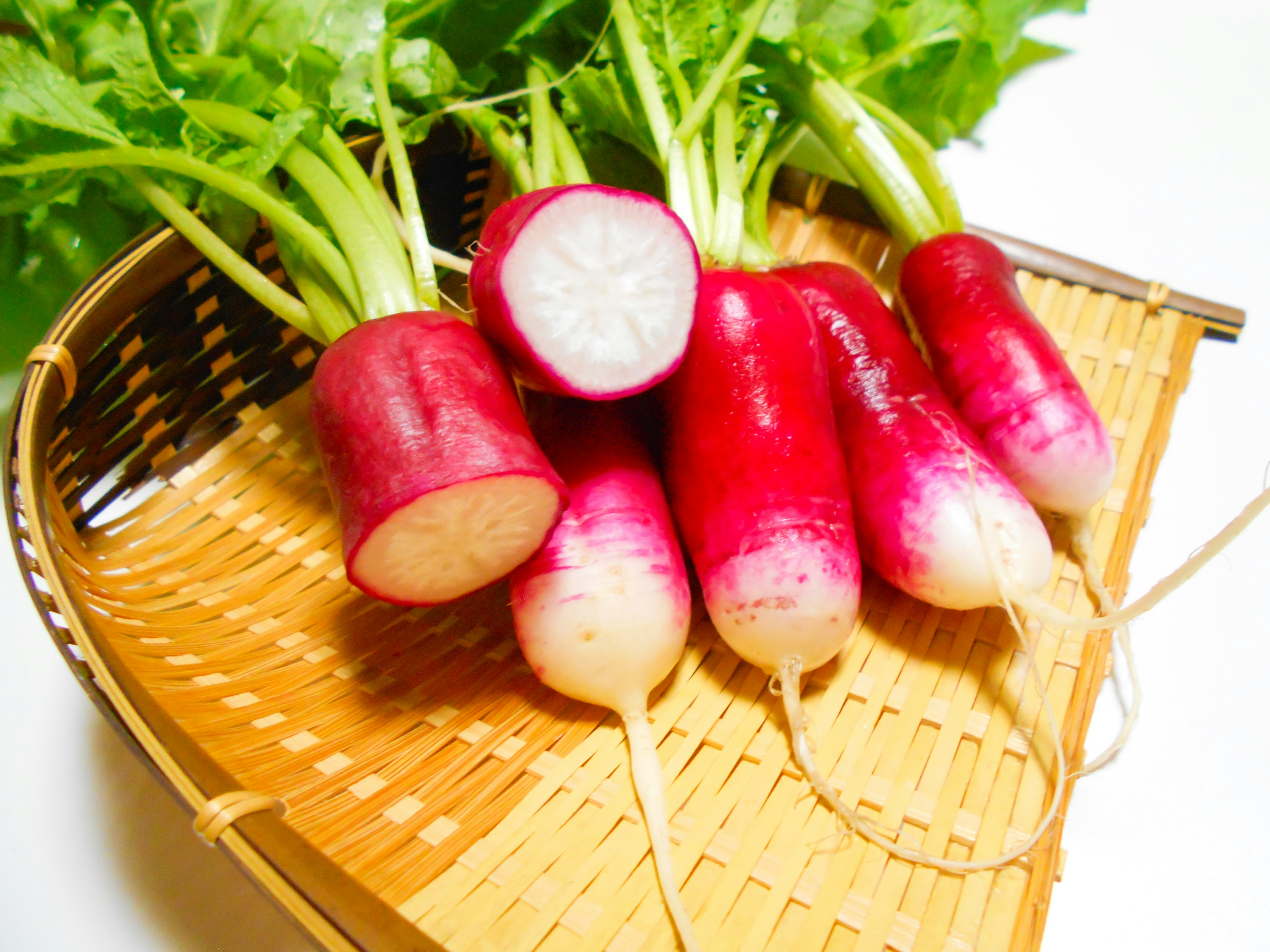 Fresh red radishes arranged in a bamboo basket