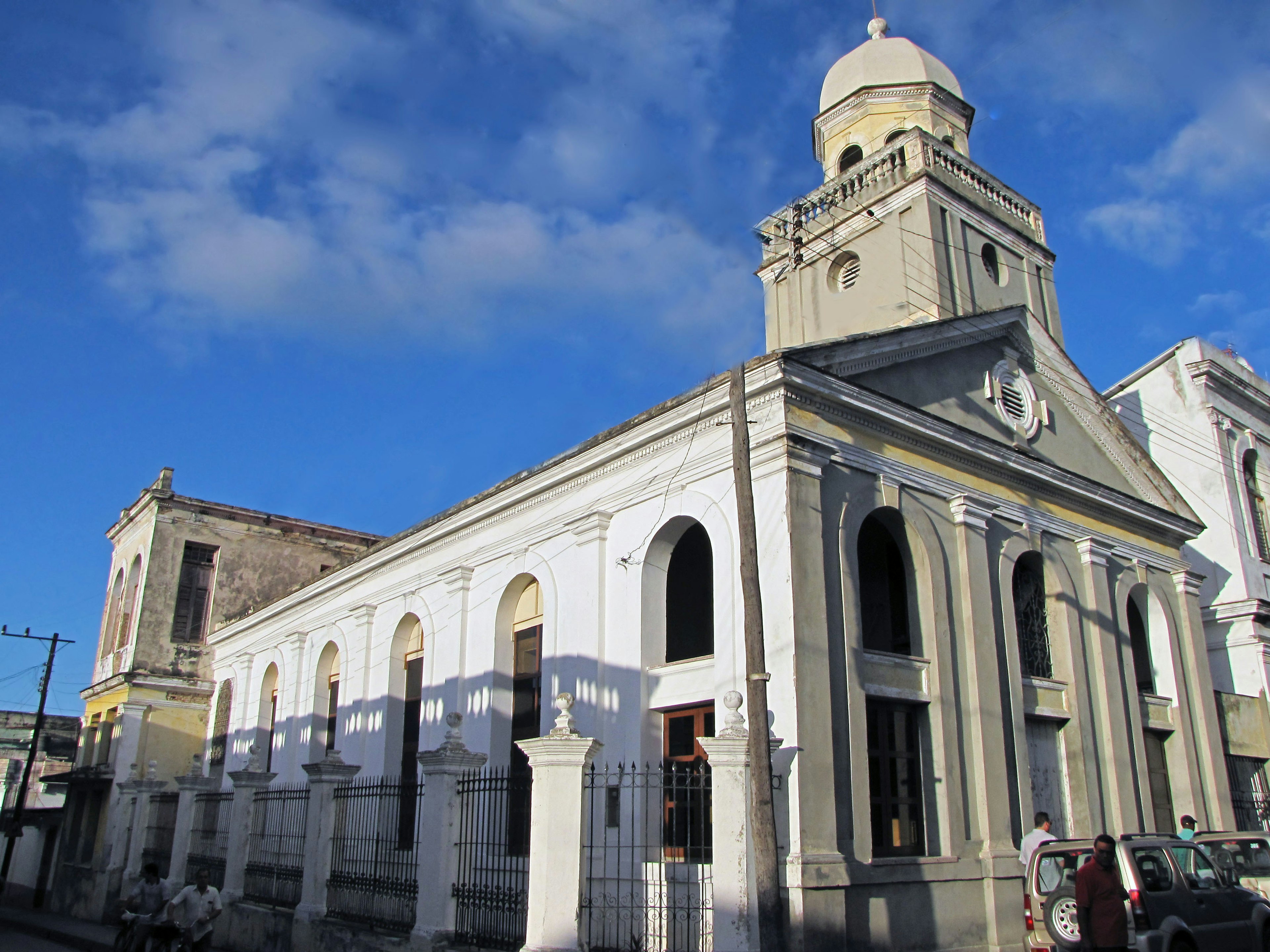 Exterior de una iglesia histórica bajo un cielo azul con un edificio blanco