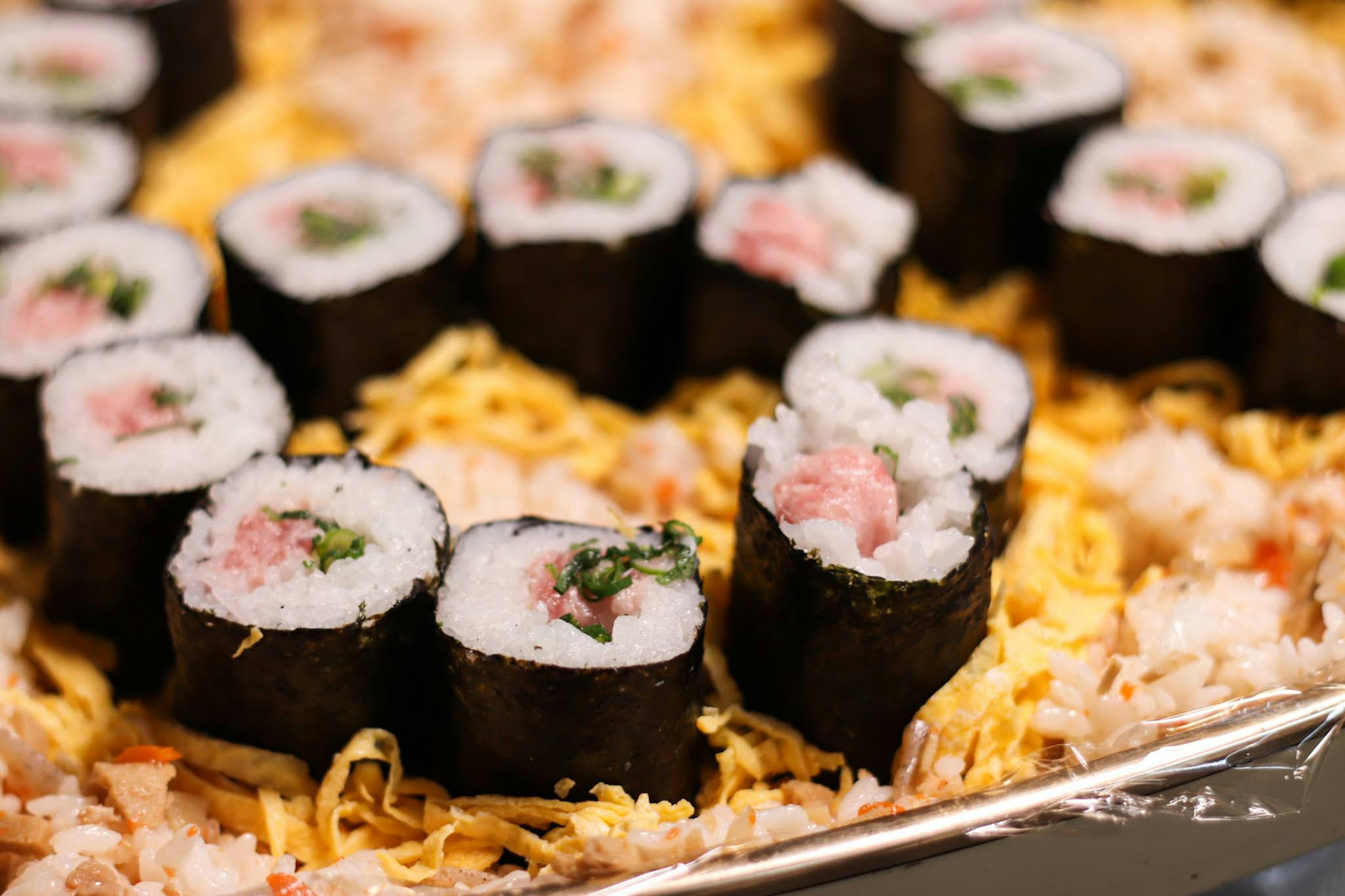 Sushi-Rollen auf einem Bett aus Reis mit bunten Belägen angeordnet