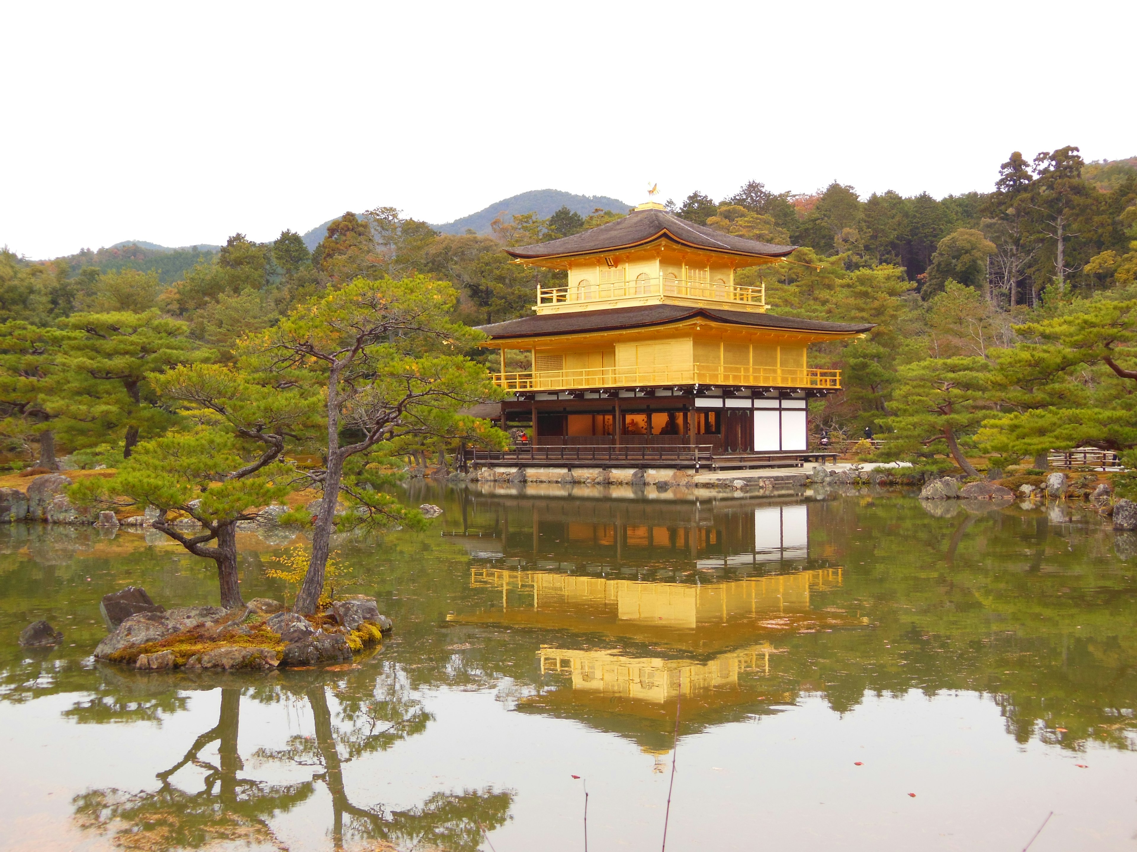 Golden pavilion reflecting in a tranquil pond surrounded by greenery