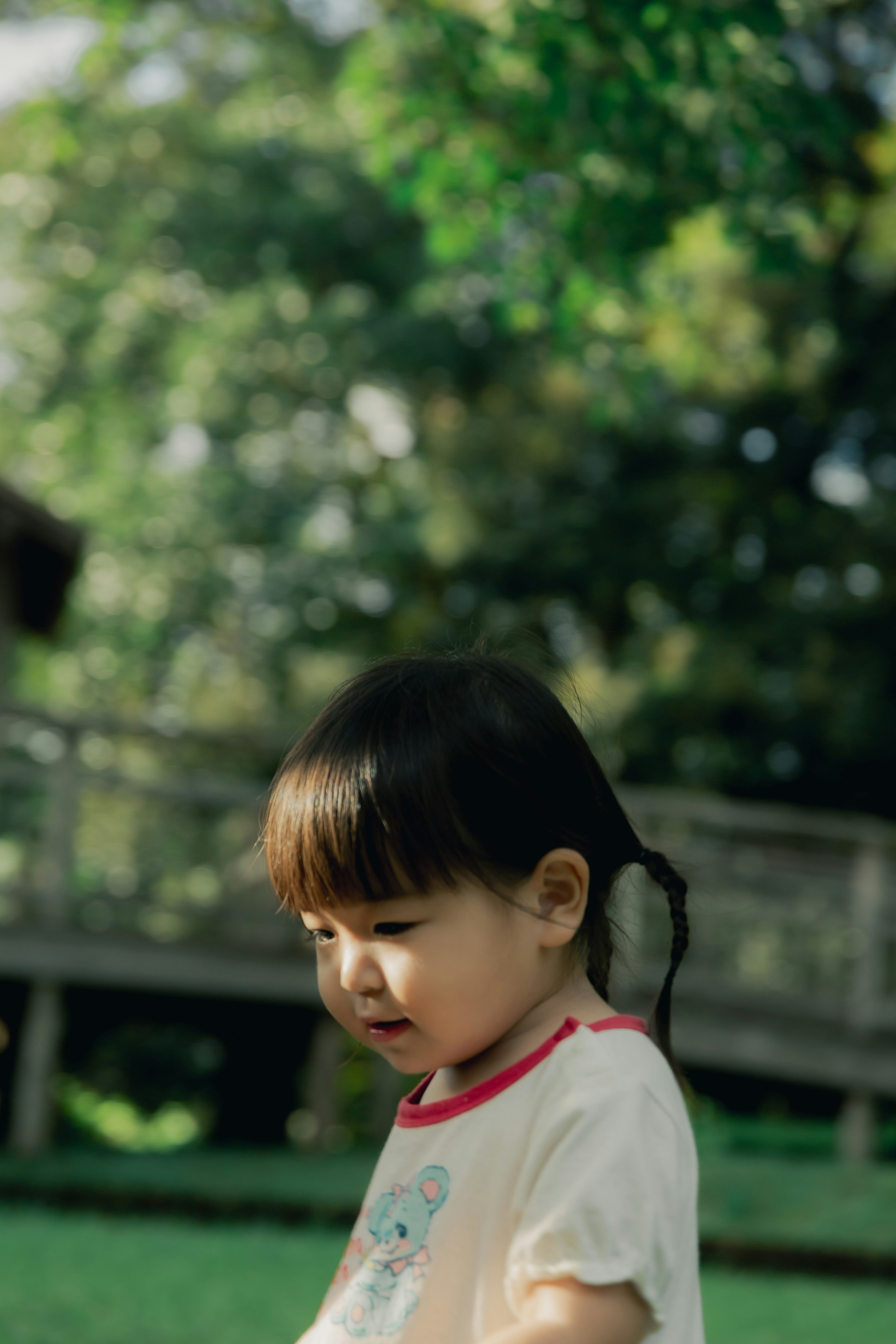 Young girl playing in a green background with pigtails showing a cute expression