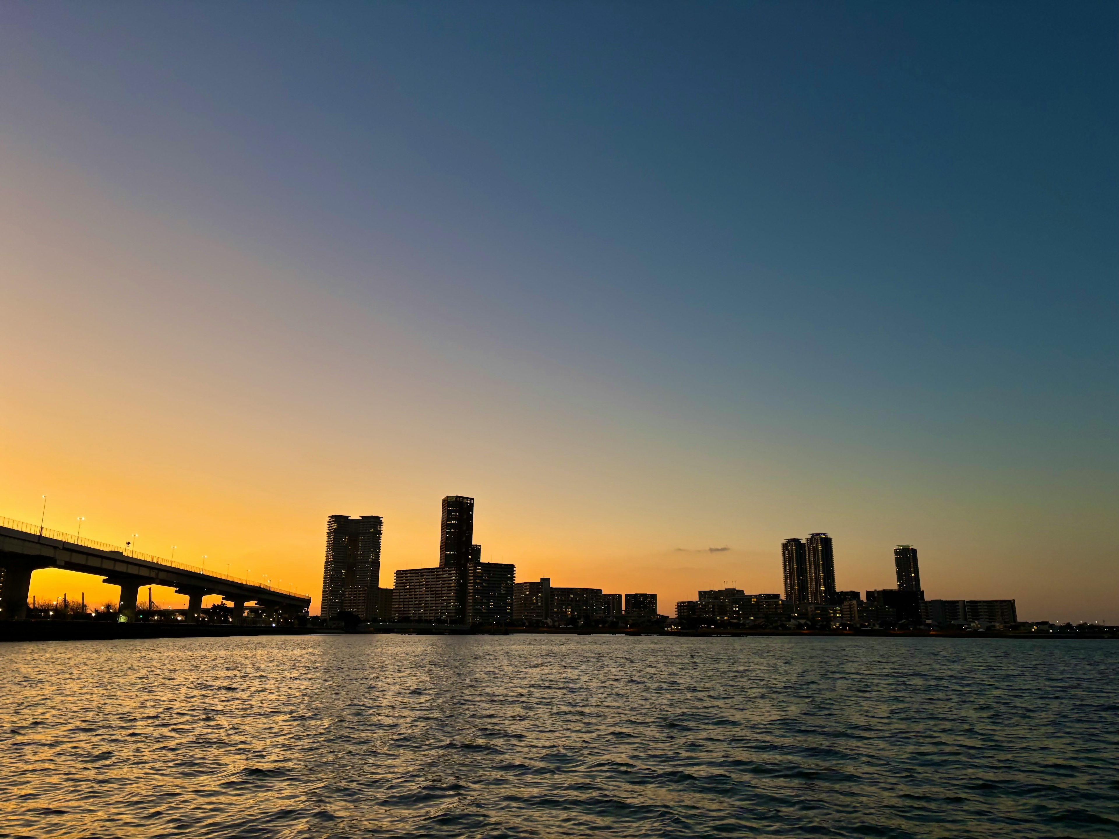 夕焼けの中での都市のスカイラインと水面の反射