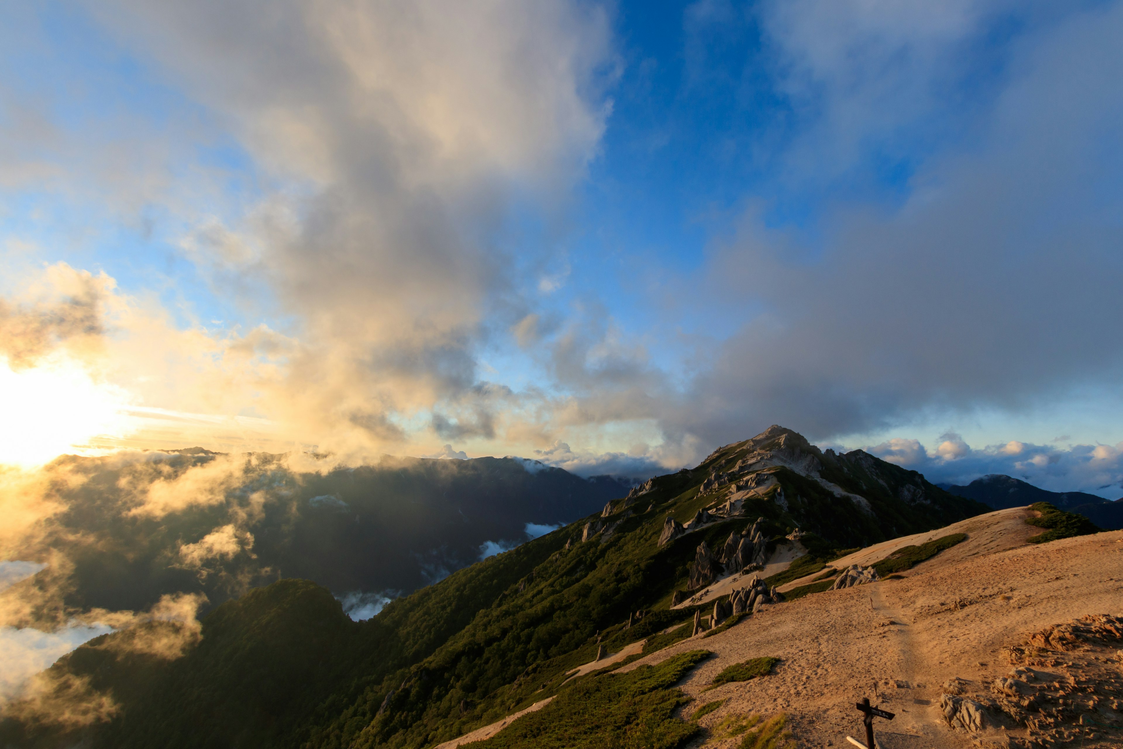 Vista escénica desde la cima de una montaña con nubes y luz solar