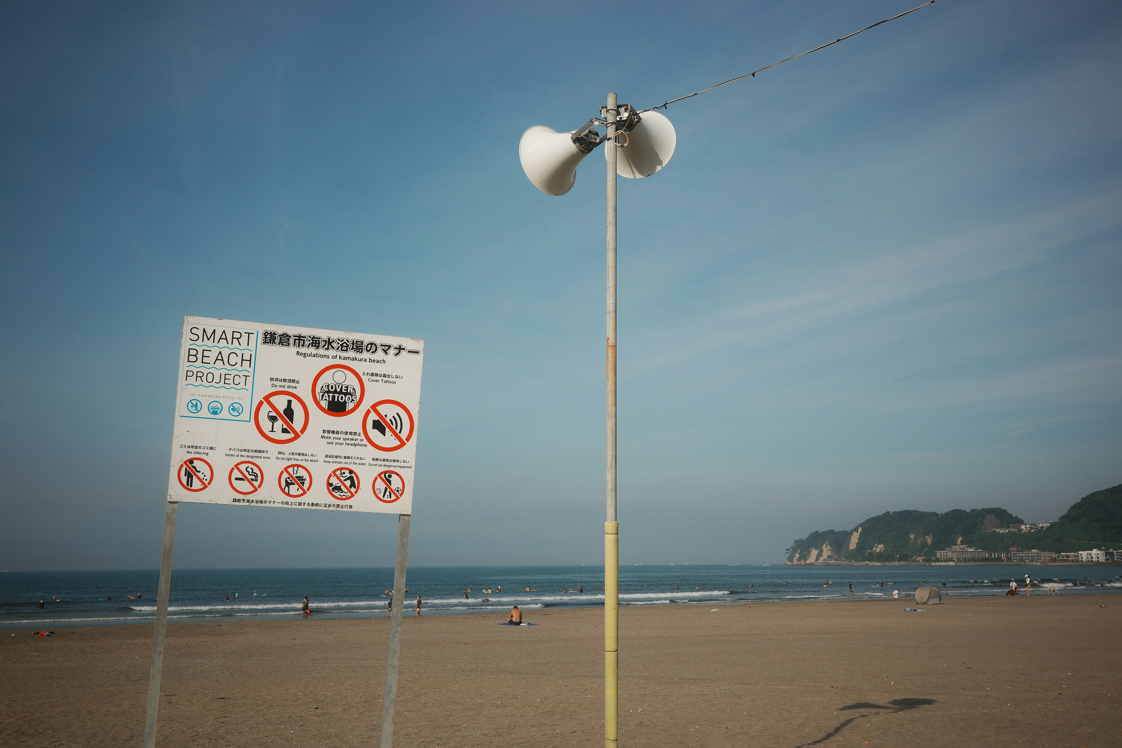 Pemandangan pantai dengan papan peringatan dan speaker