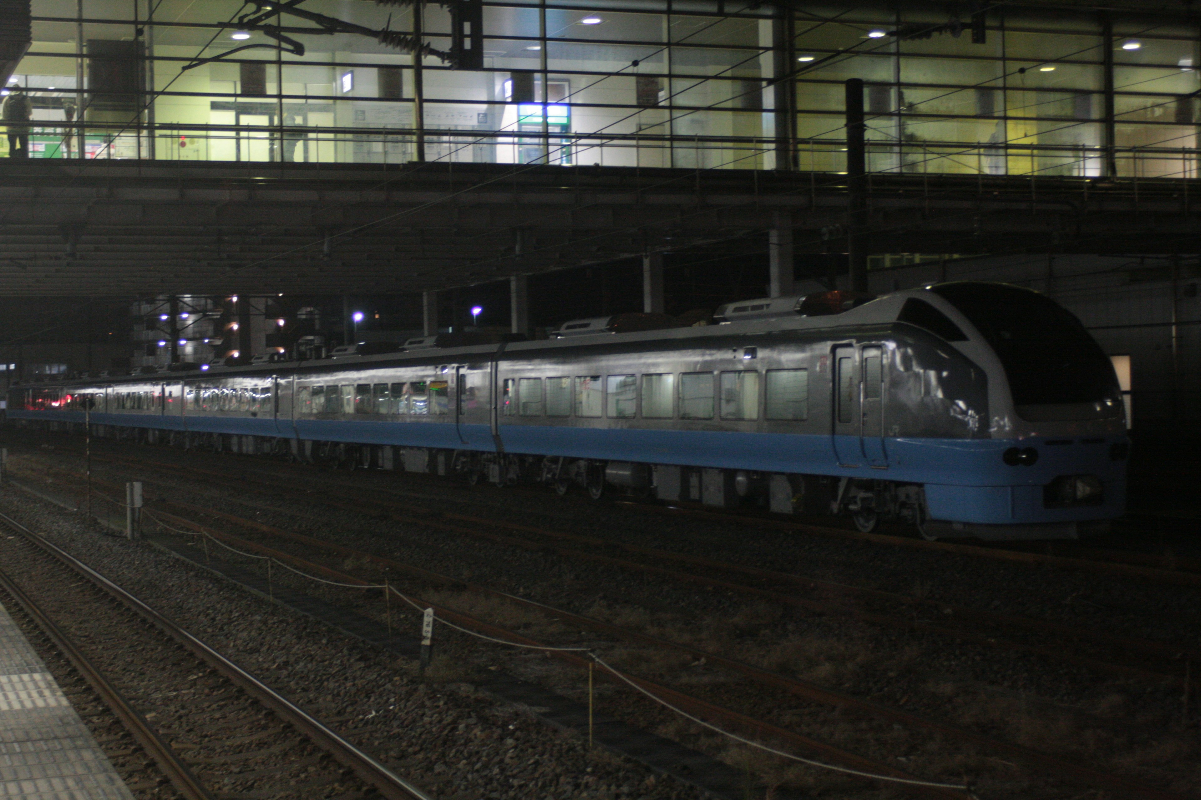 A blue train parked at a station at night