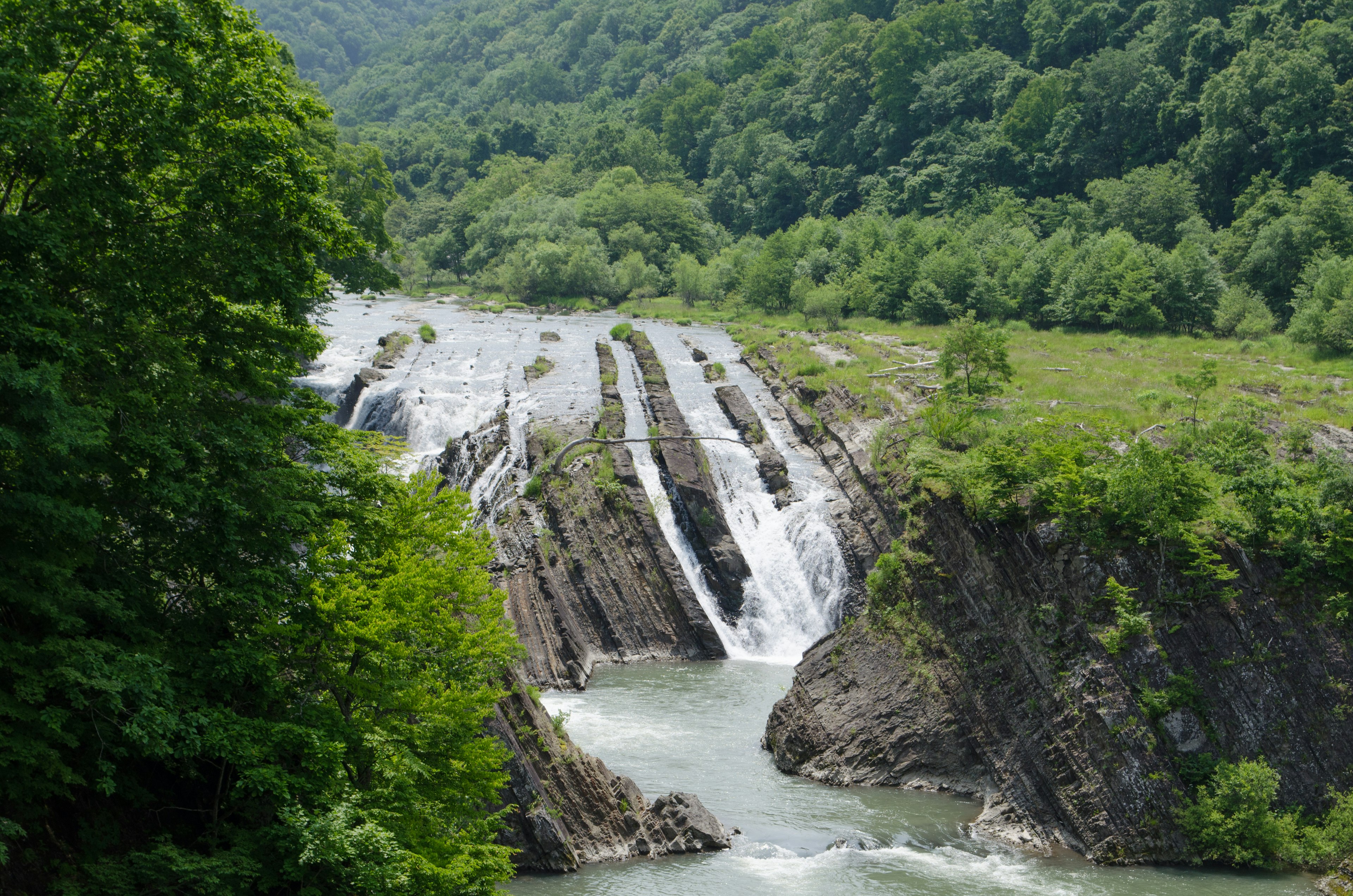 Cascata panoramica circondata da montagne verdeggianti