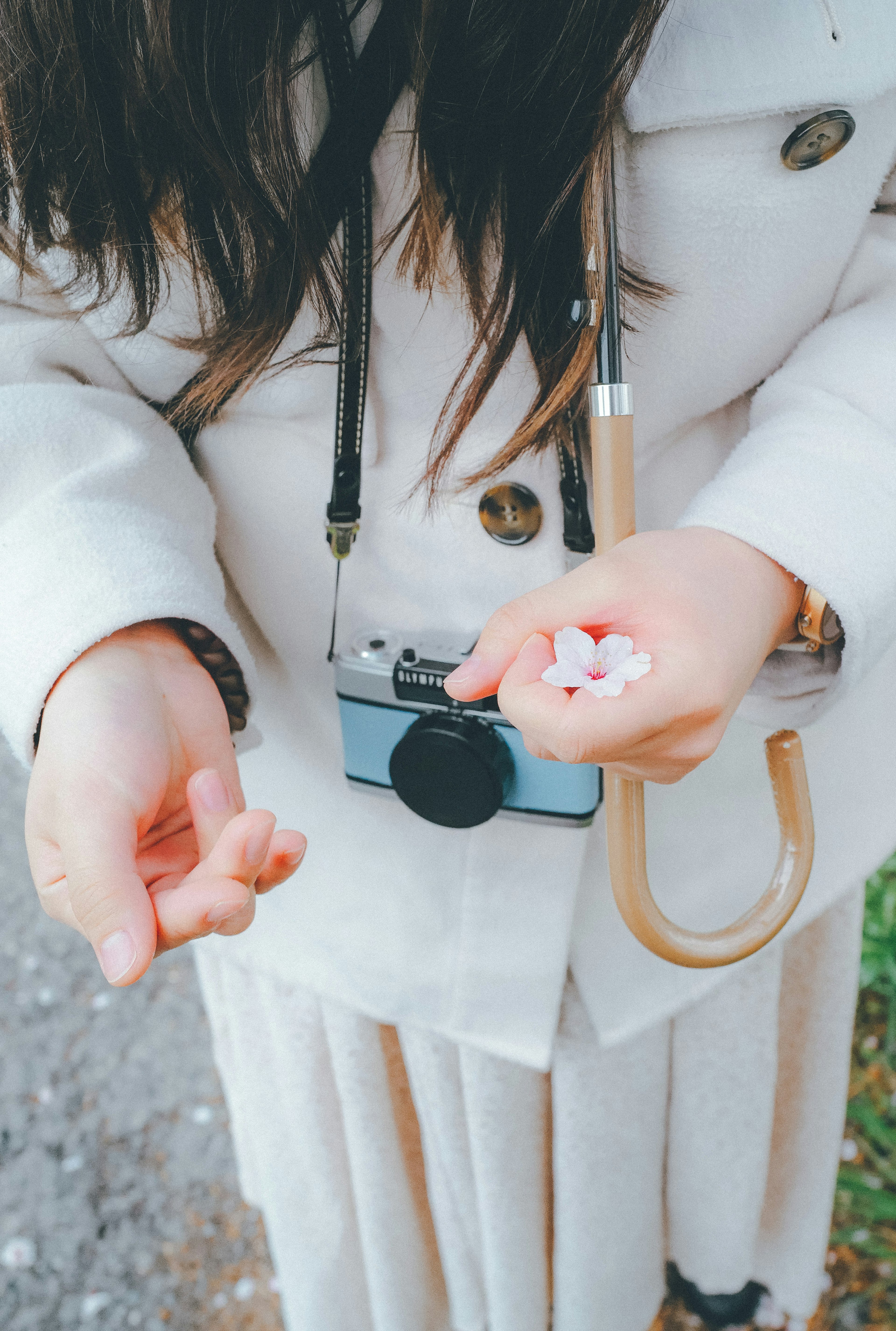 Femme tenant de petits objets dans ses mains avec un appareil photo autour du cou