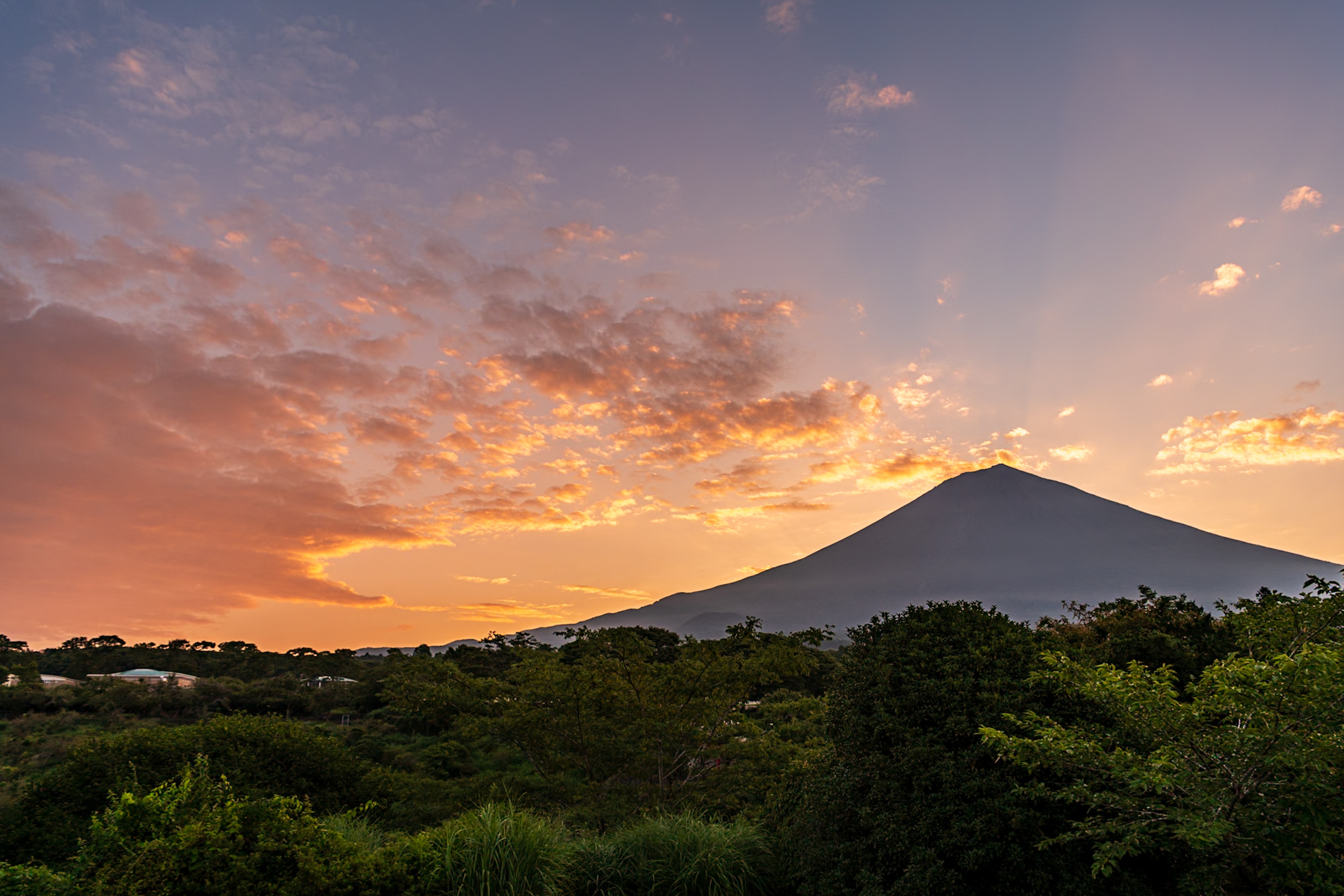 Maestoso Monte Agung contro un cielo di tramonto vibrante e una vegetazione lussureggiante