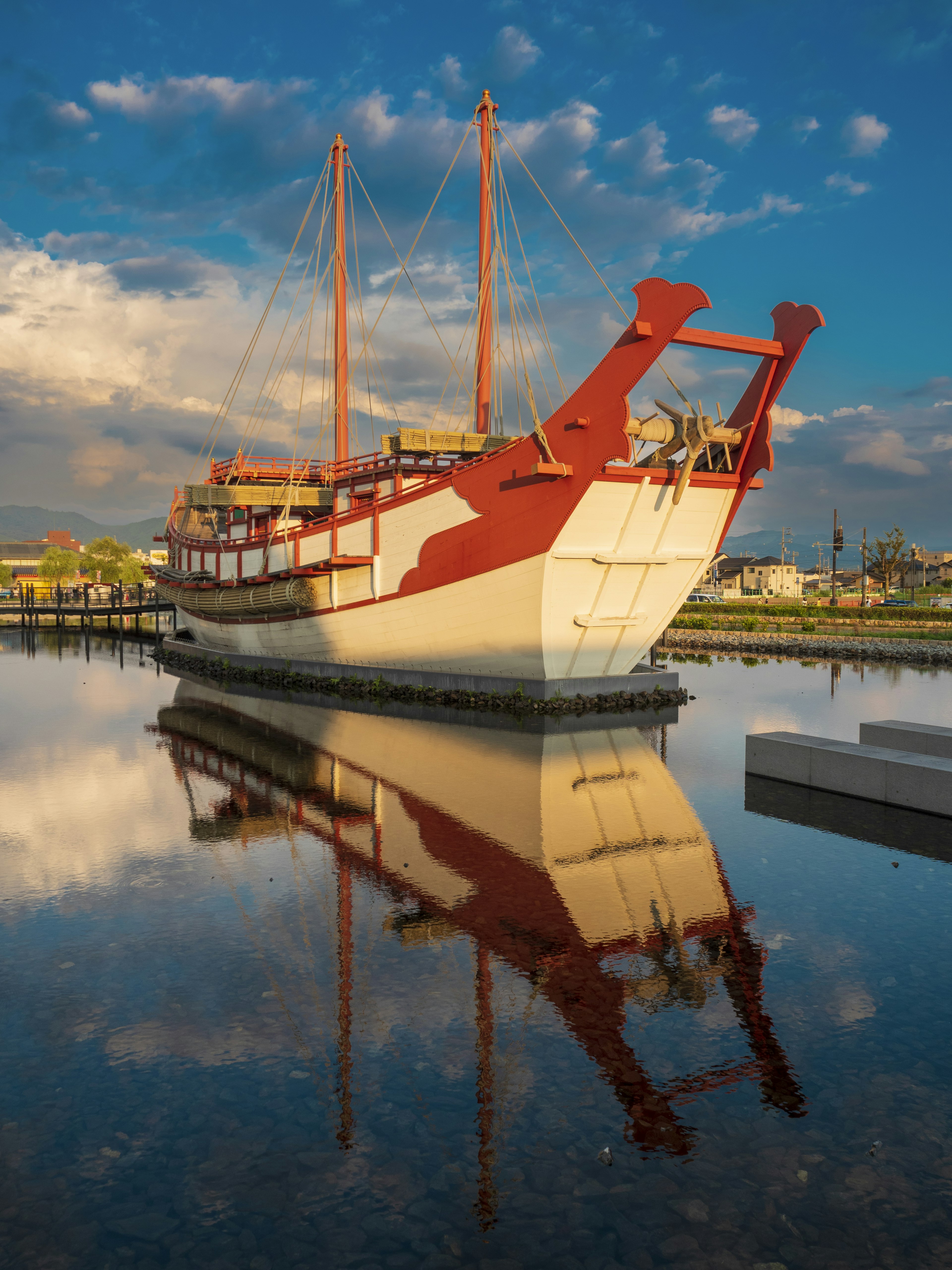 A red and white ship reflecting on calm water under a blue sky