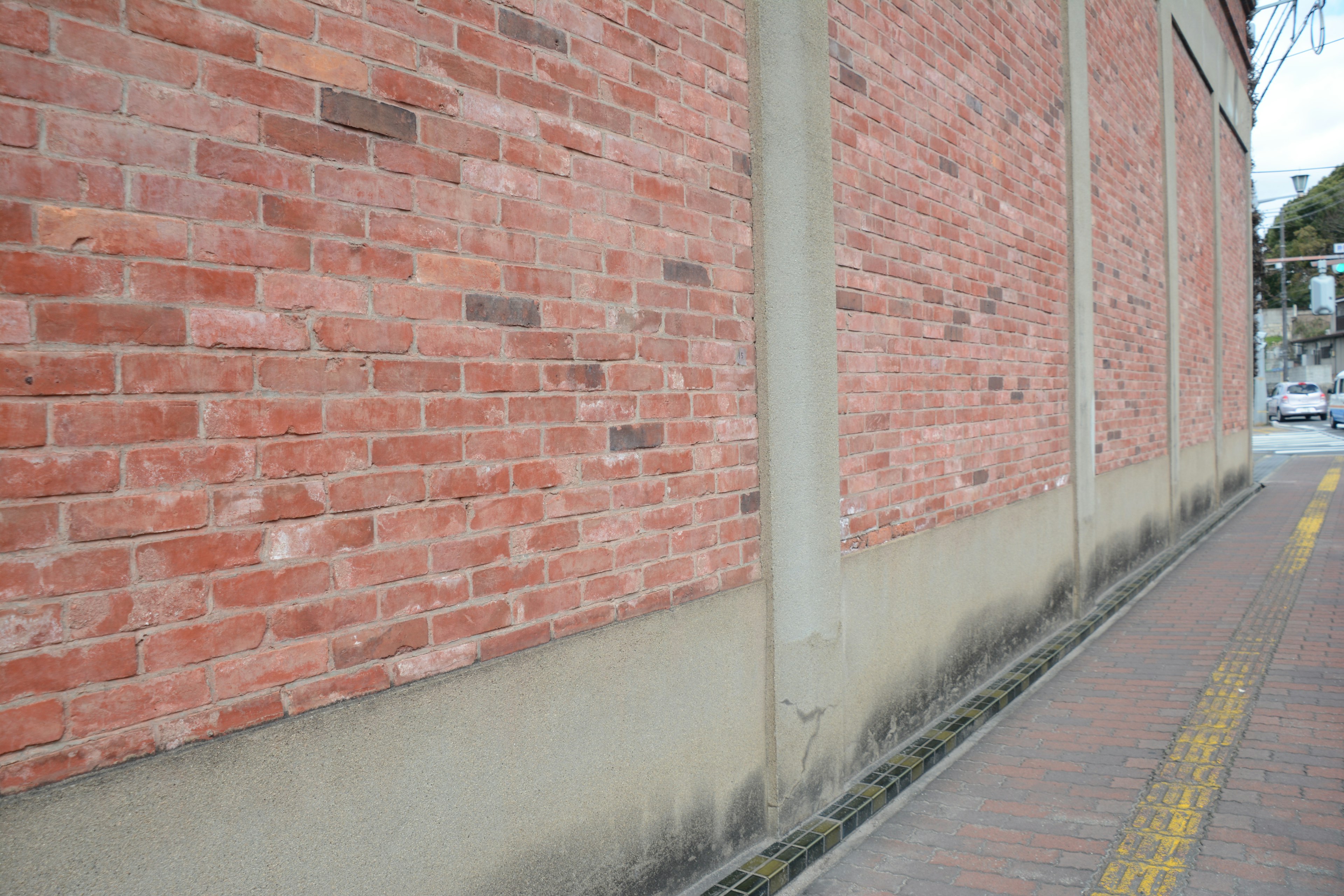 Section d'une rue avec un mur en briques rouges et une fondation en béton