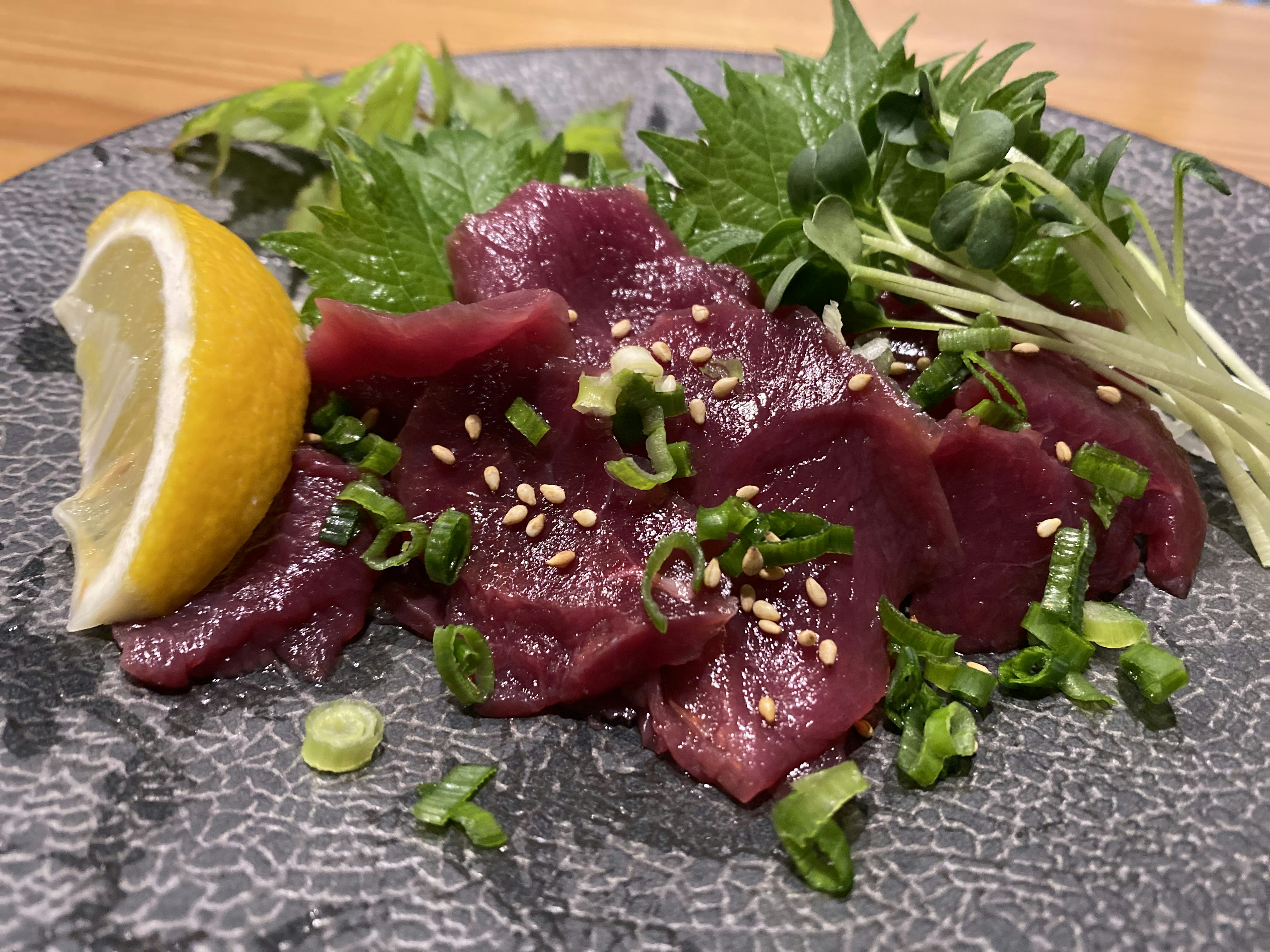 Sashimi de cheval frais servi avec du citron et des garnitures