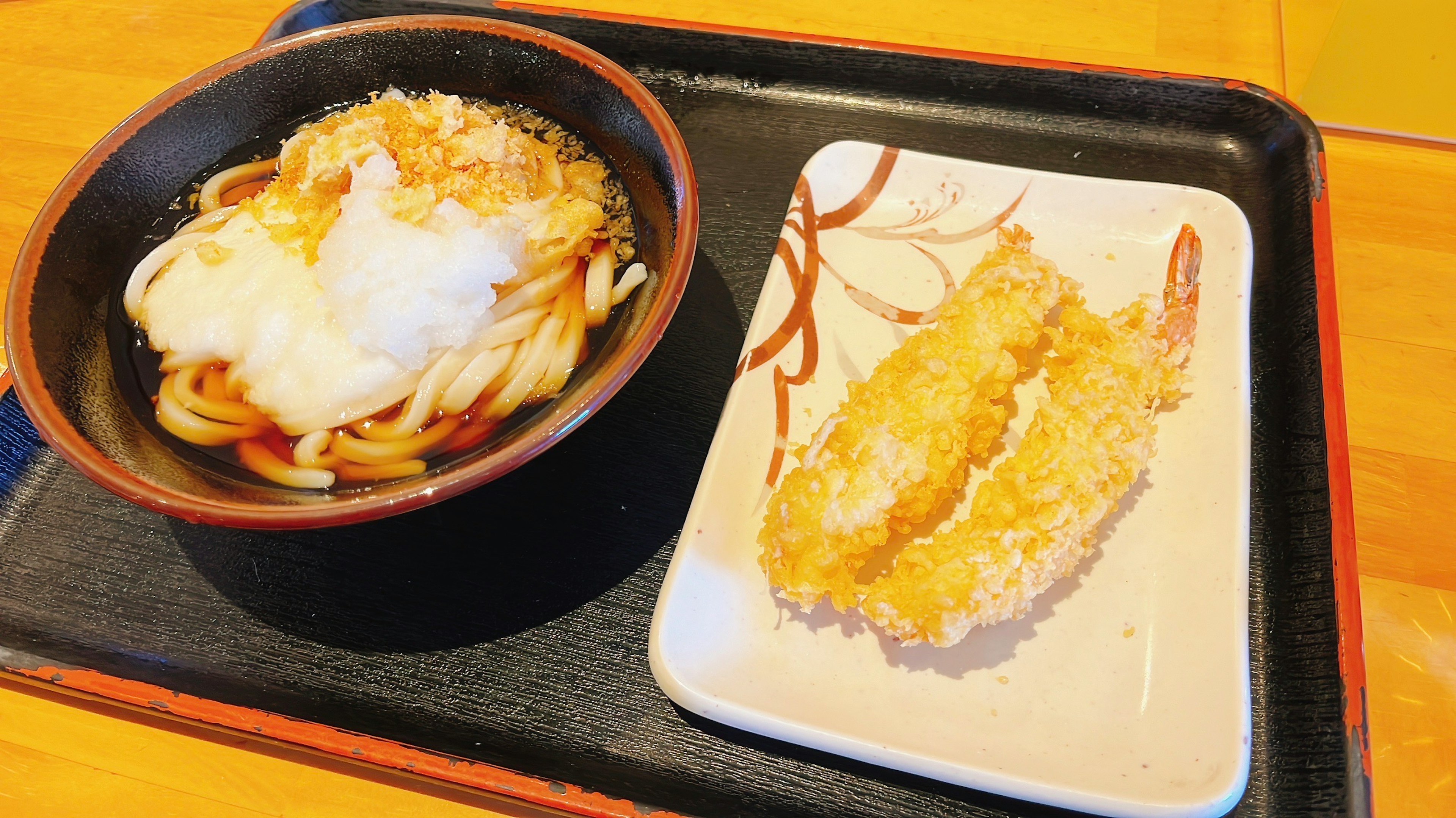 Udon noodles with tempura shrimp served on a tray