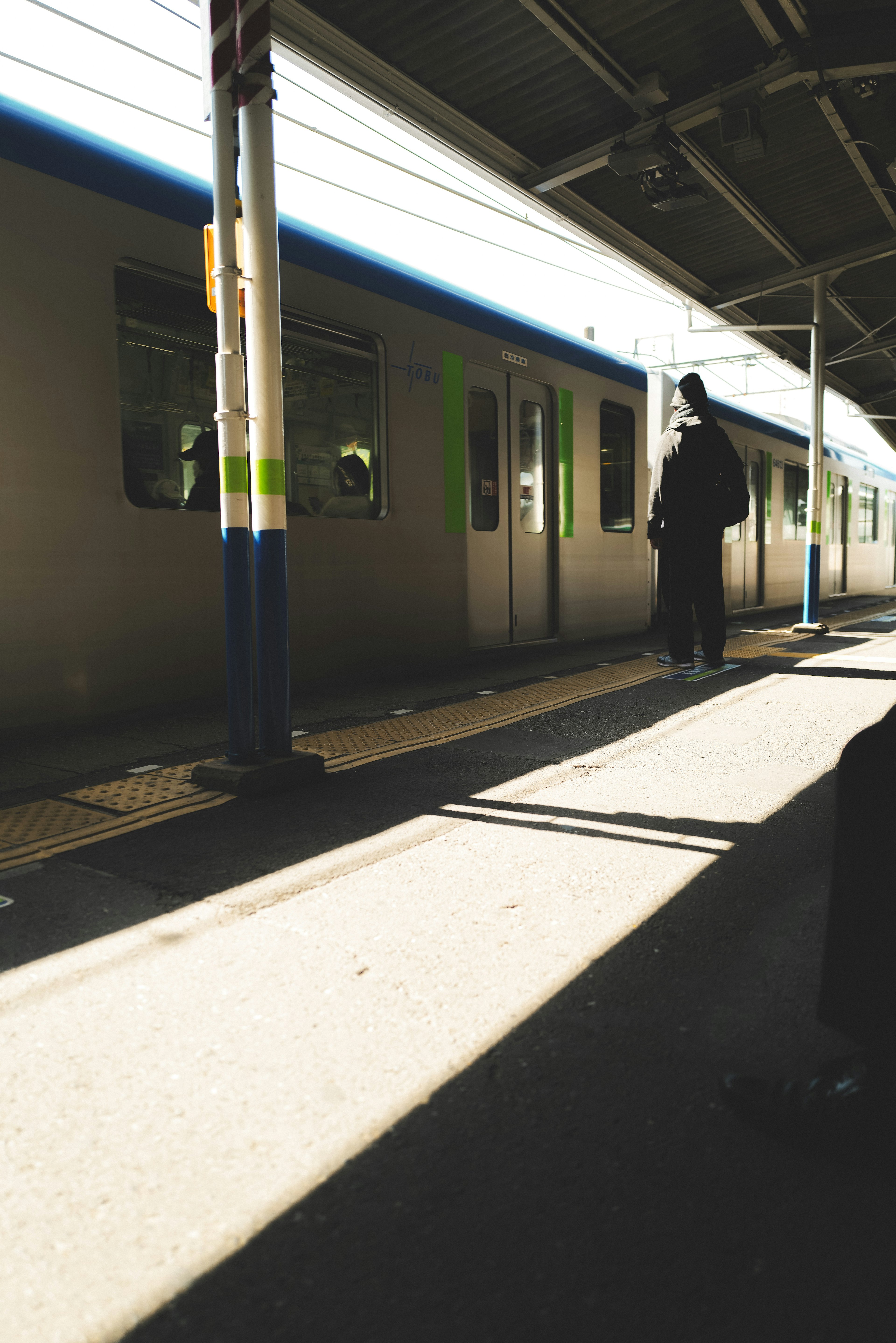 A shadow of a person waiting at a quiet train station with bright light