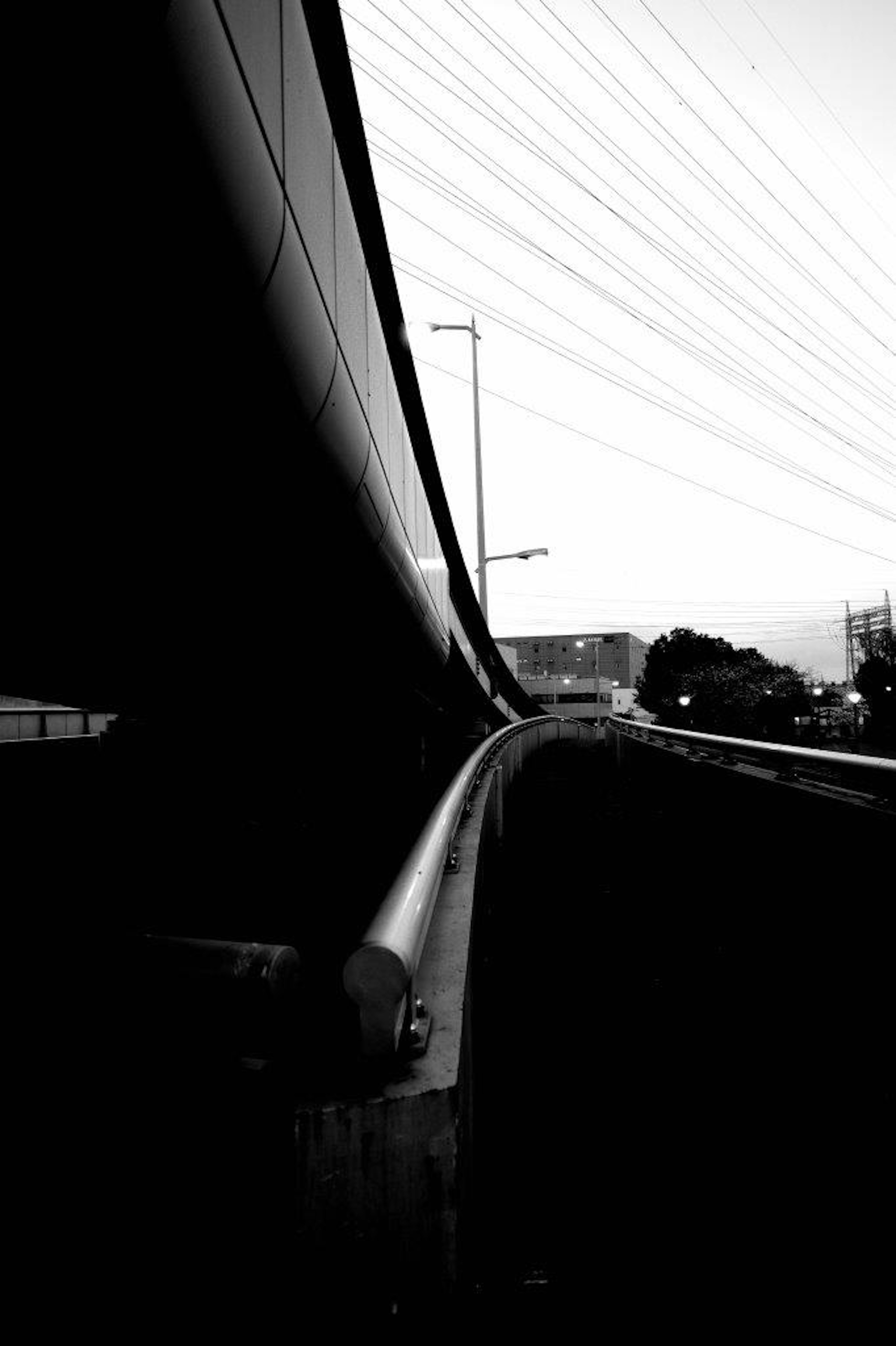 Curved black and white road with visible power lines