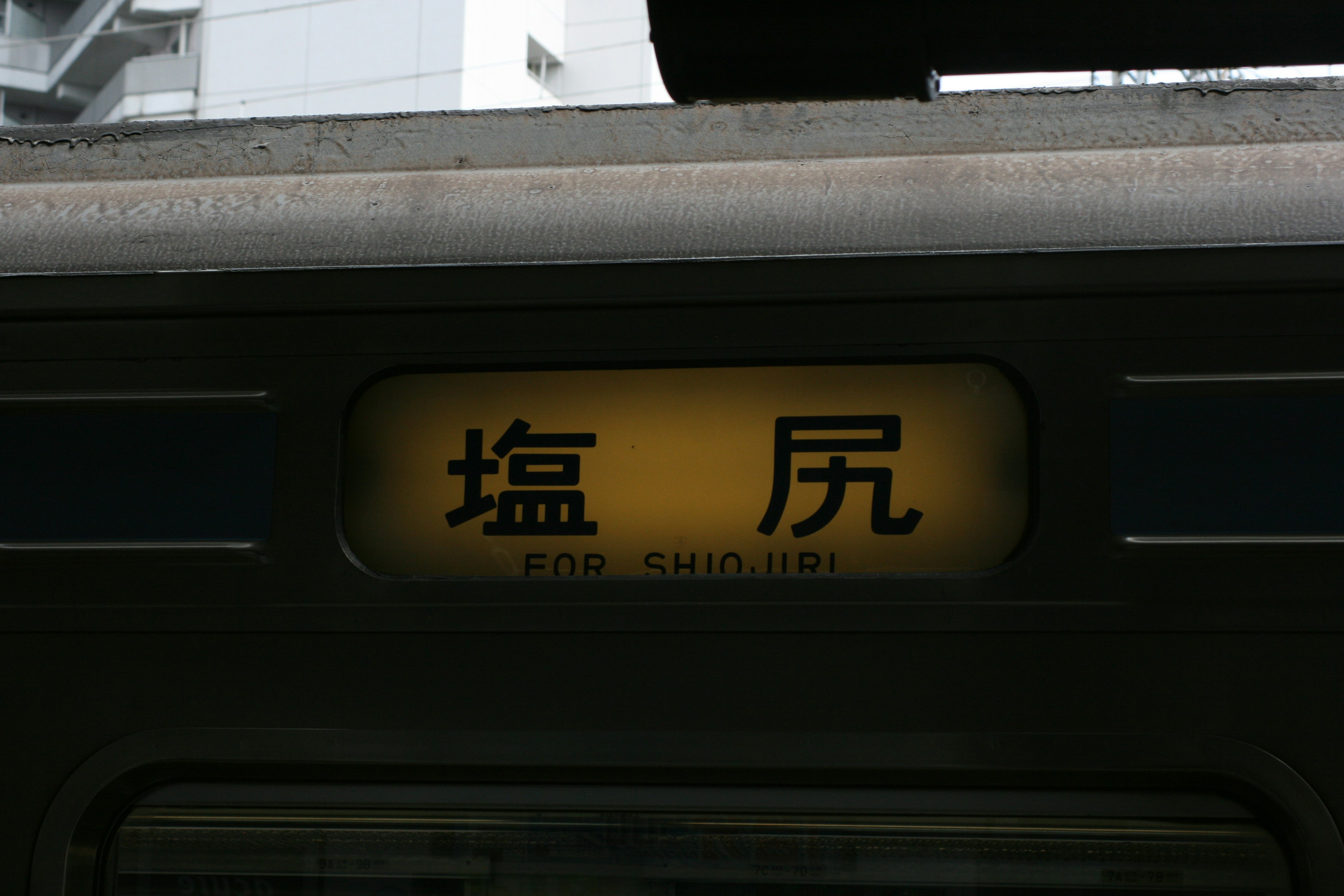 Schild für den Bahnhof Shiojiri mit Gebäuden im Hintergrund