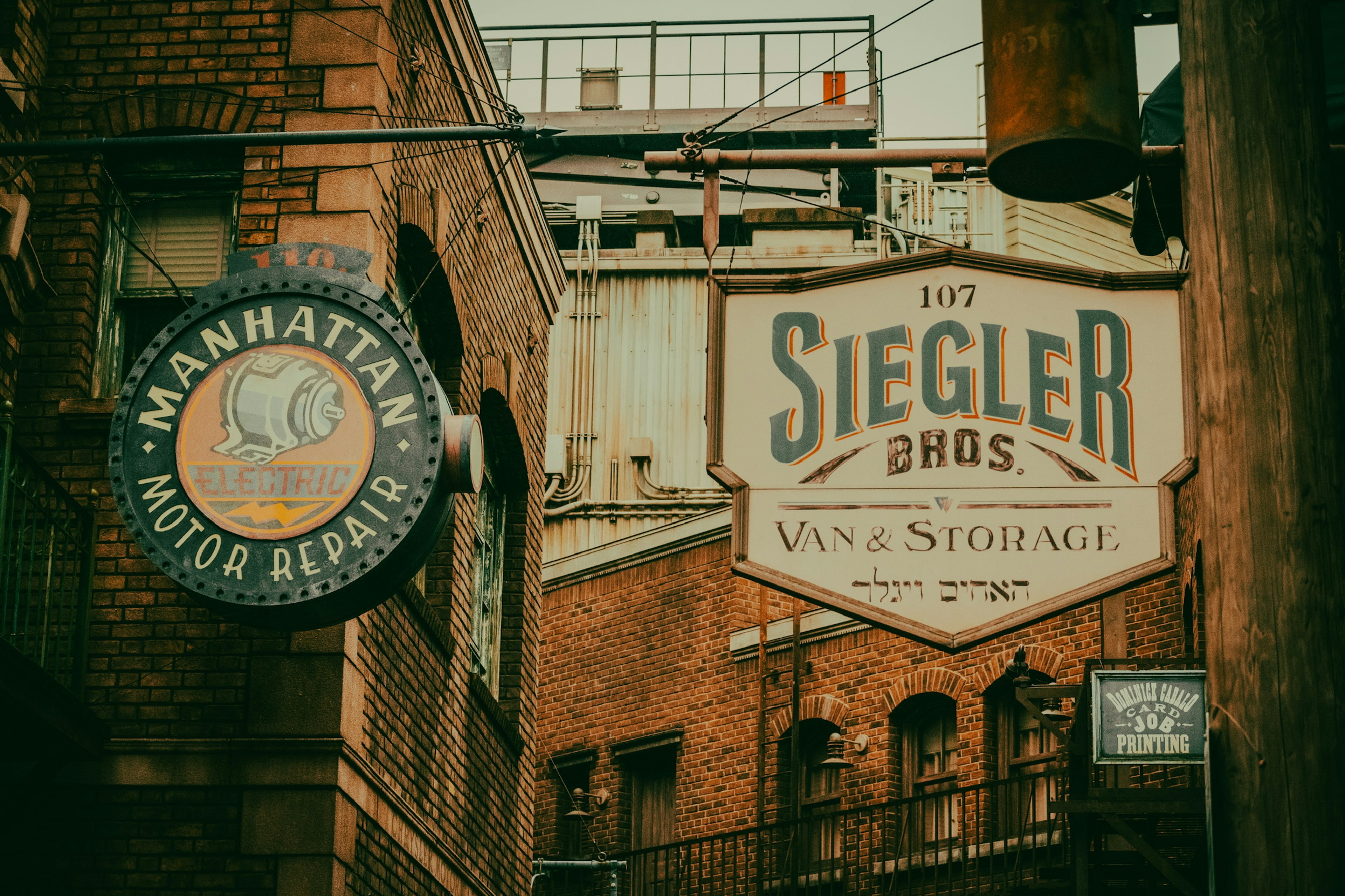 Strada storica con insegne di Manhattan Motor Repair e Siegler Bros Vintage Storage