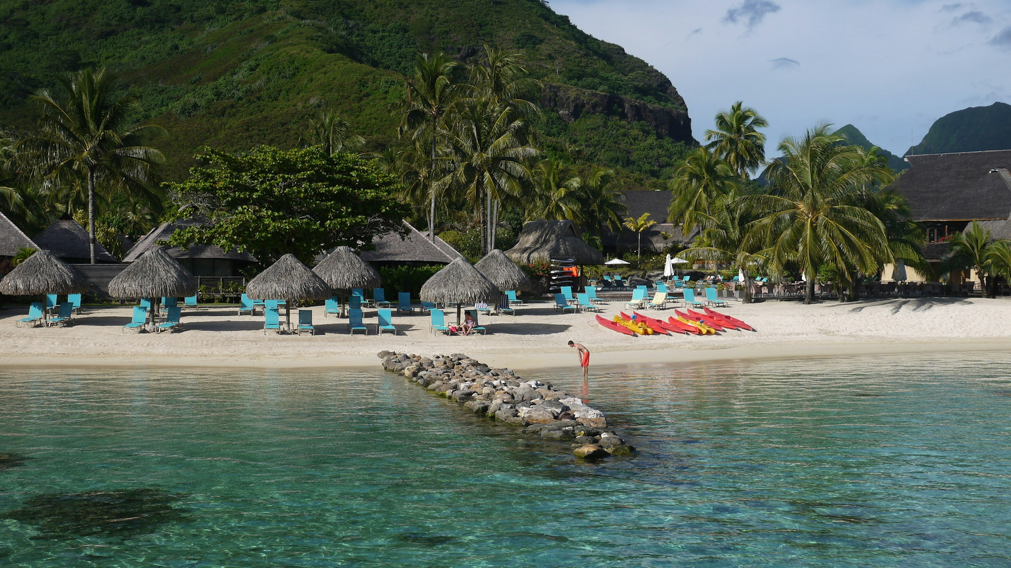 Scenic beach view with resort huts turquoise water and palm trees