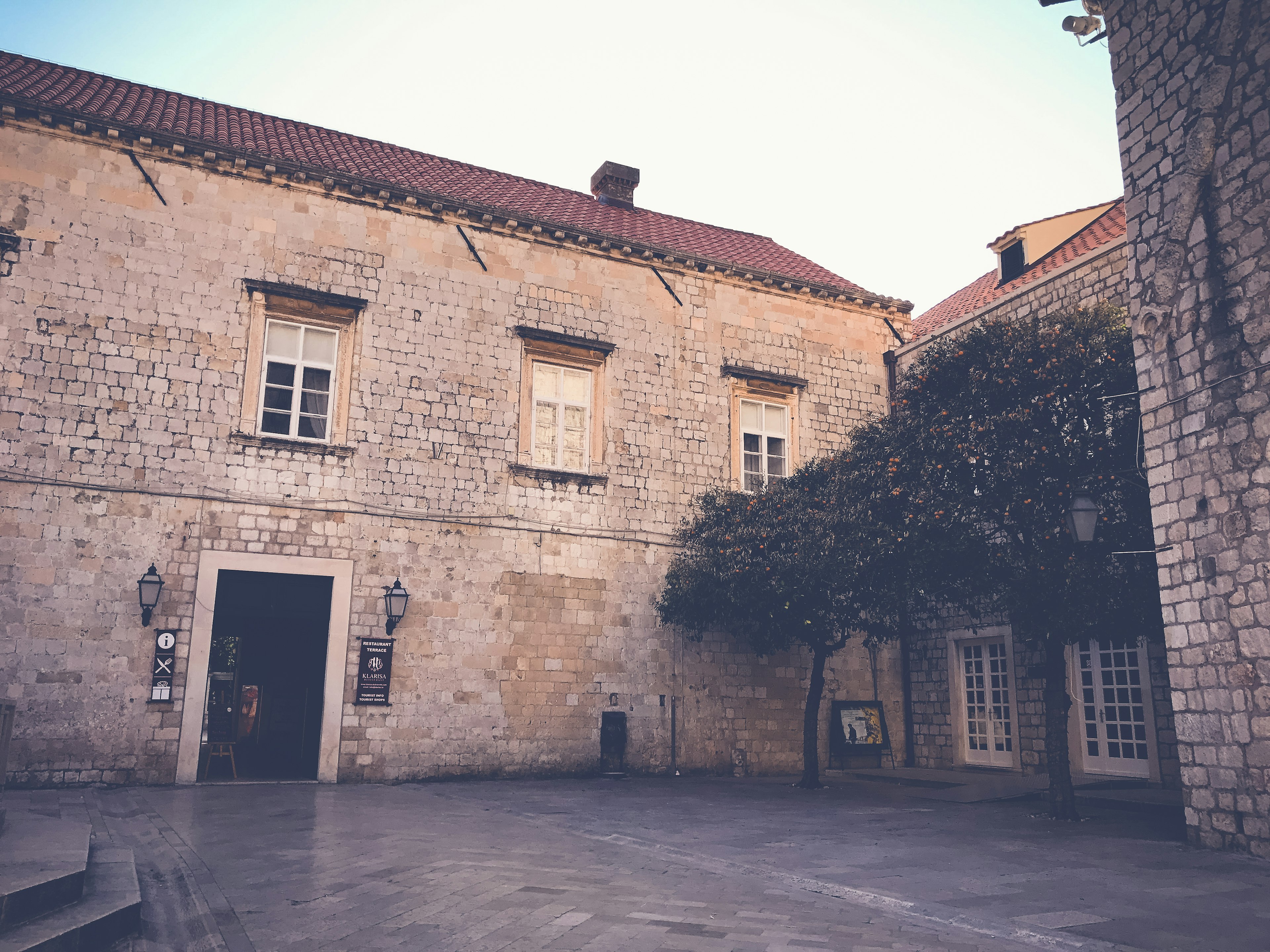 Edificio in pietra con alberi verdi in un cortile