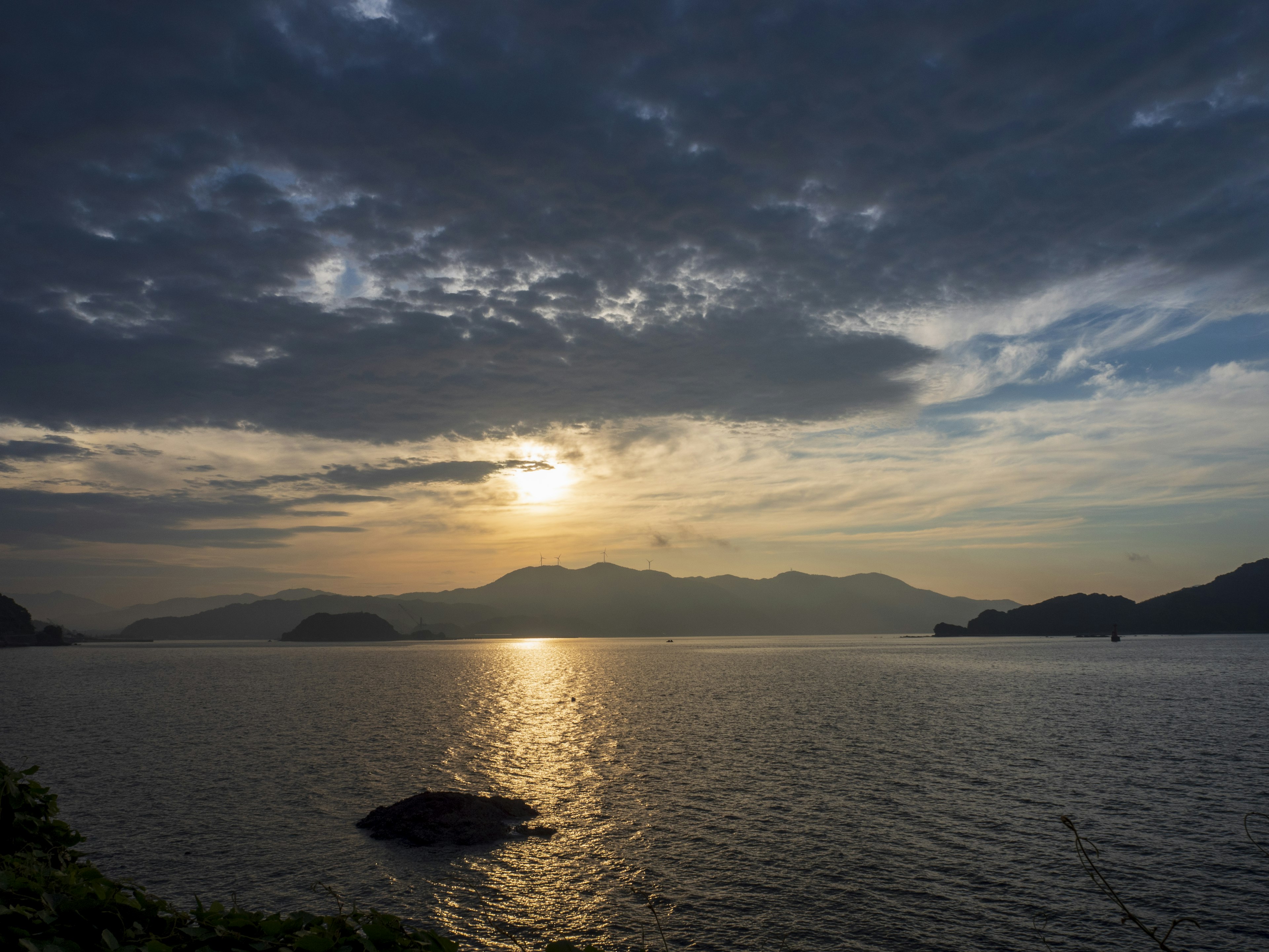 日落时宁静的湖泊场景，背景有山和云