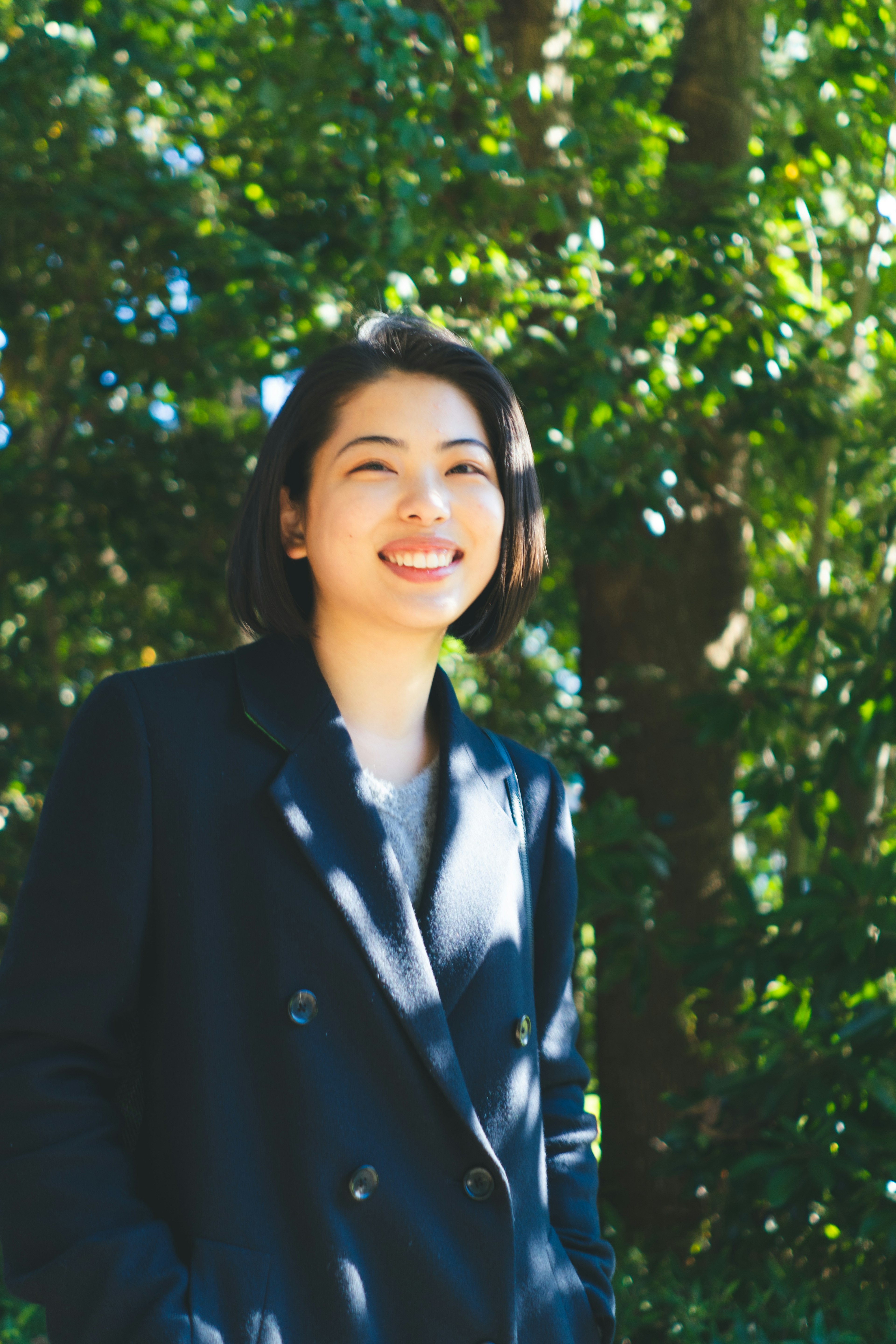 A woman smiling in front of green trees