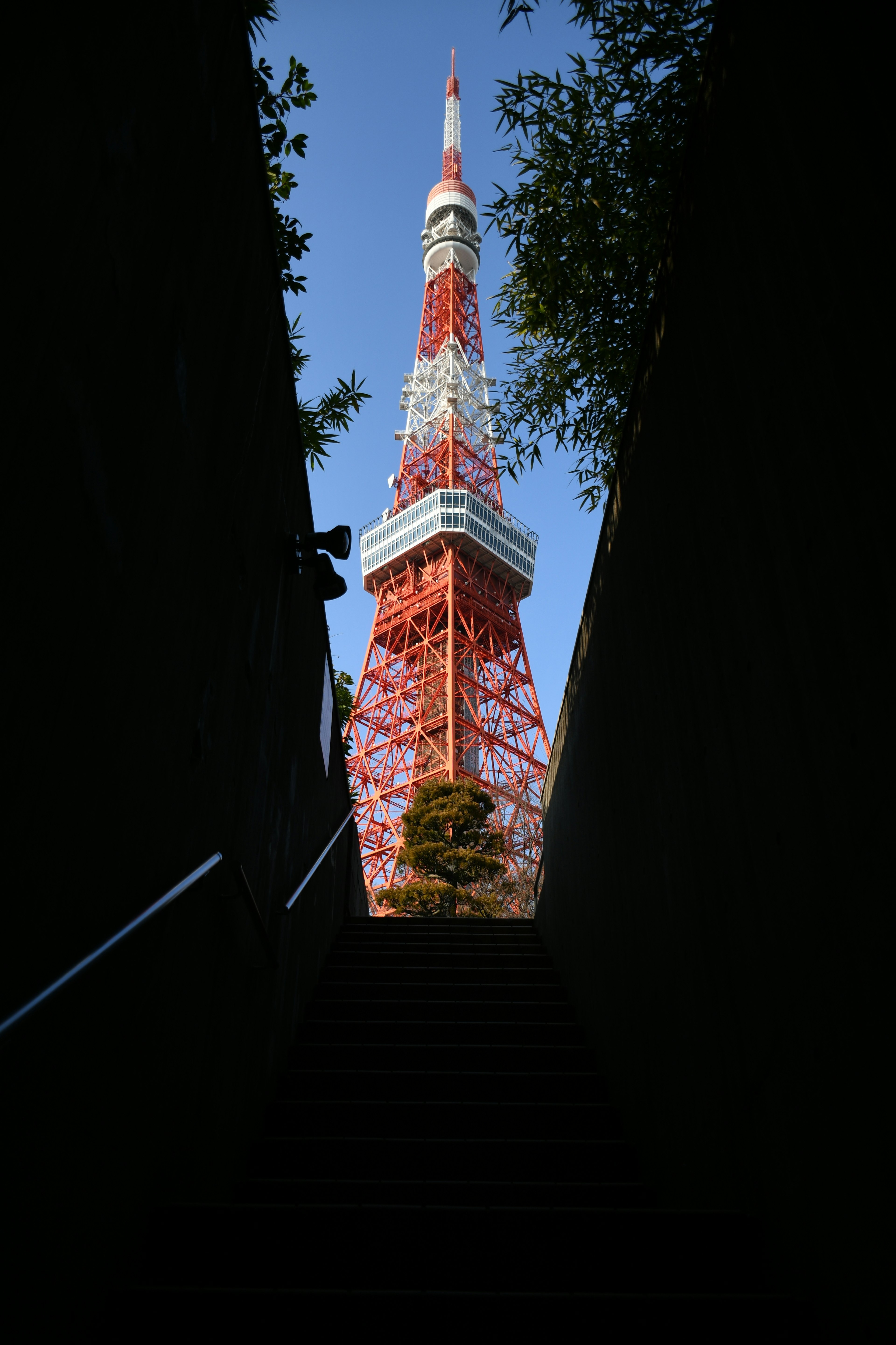 Blick auf den Tokyo Tower von den Treppen unter einem hellblauen Himmel