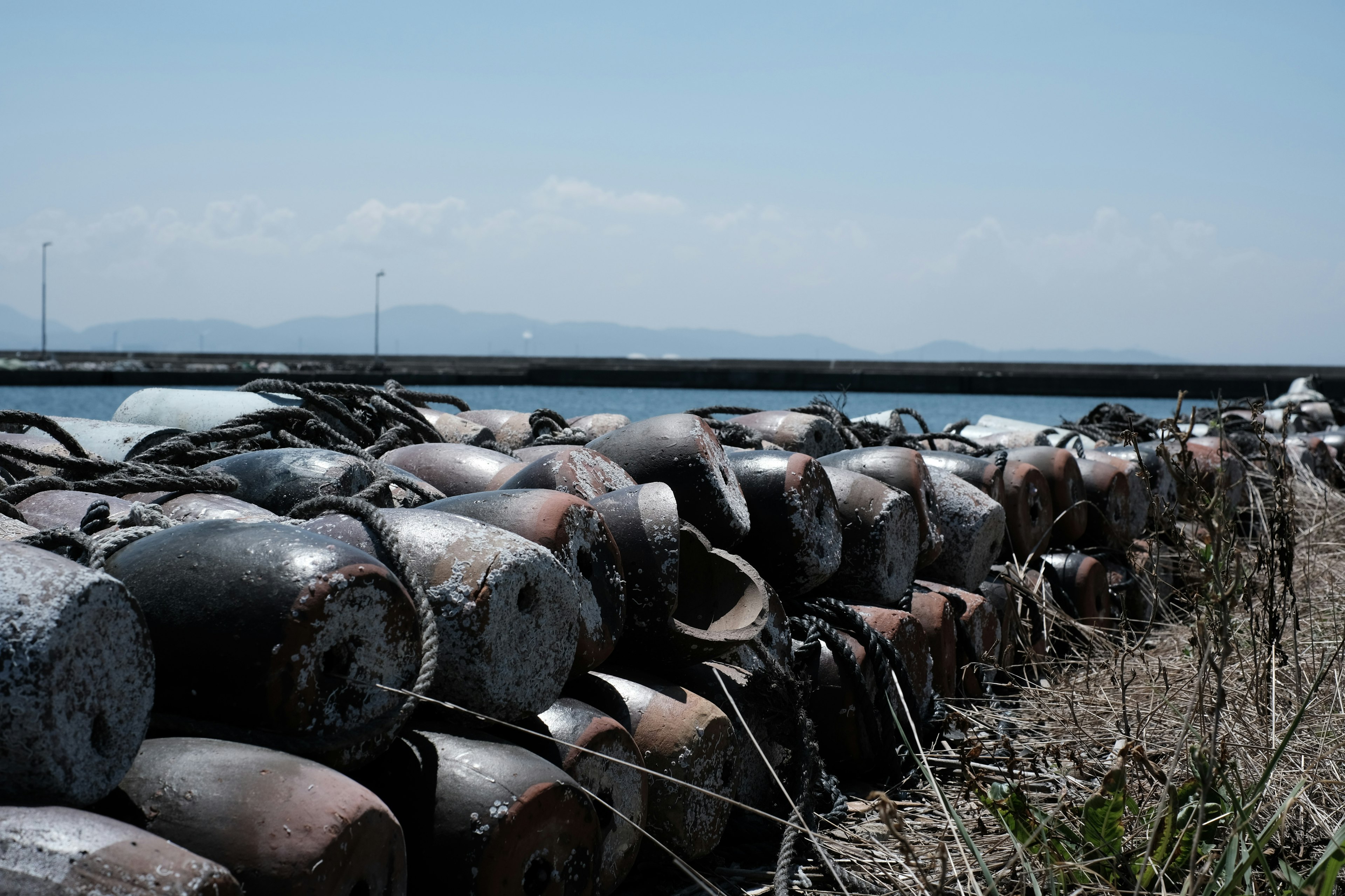 Old buoys lined along the coast under a blue sky