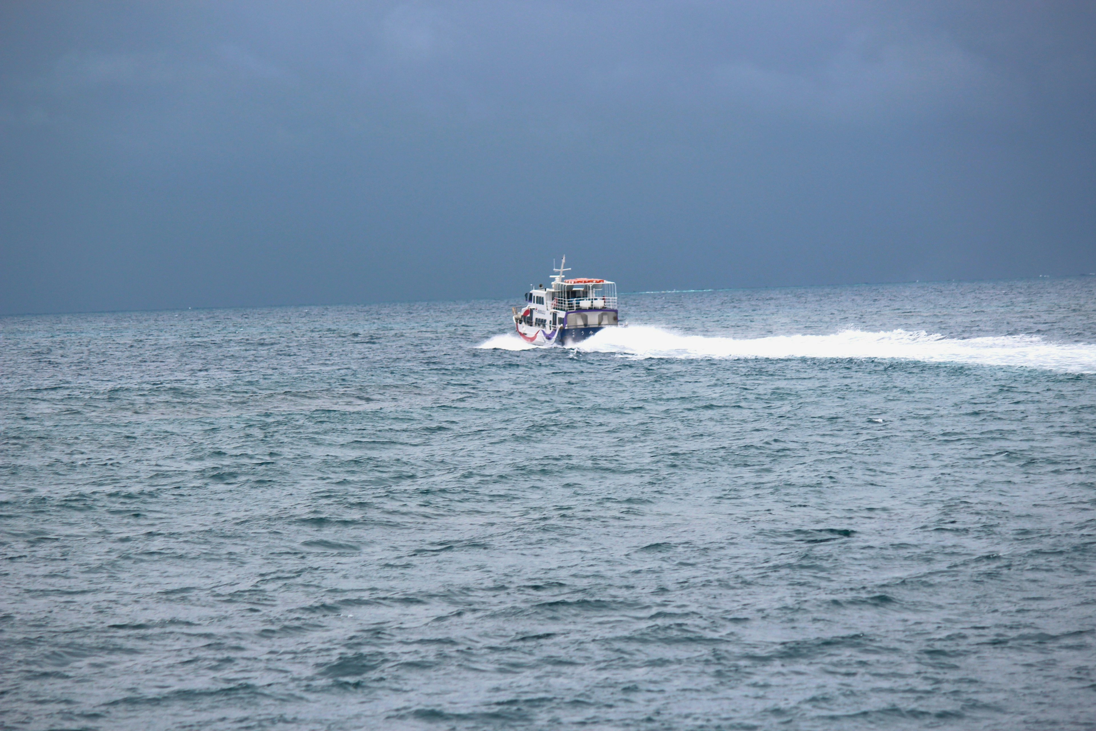 A boat speeding across the ocean with dark clouds in the background