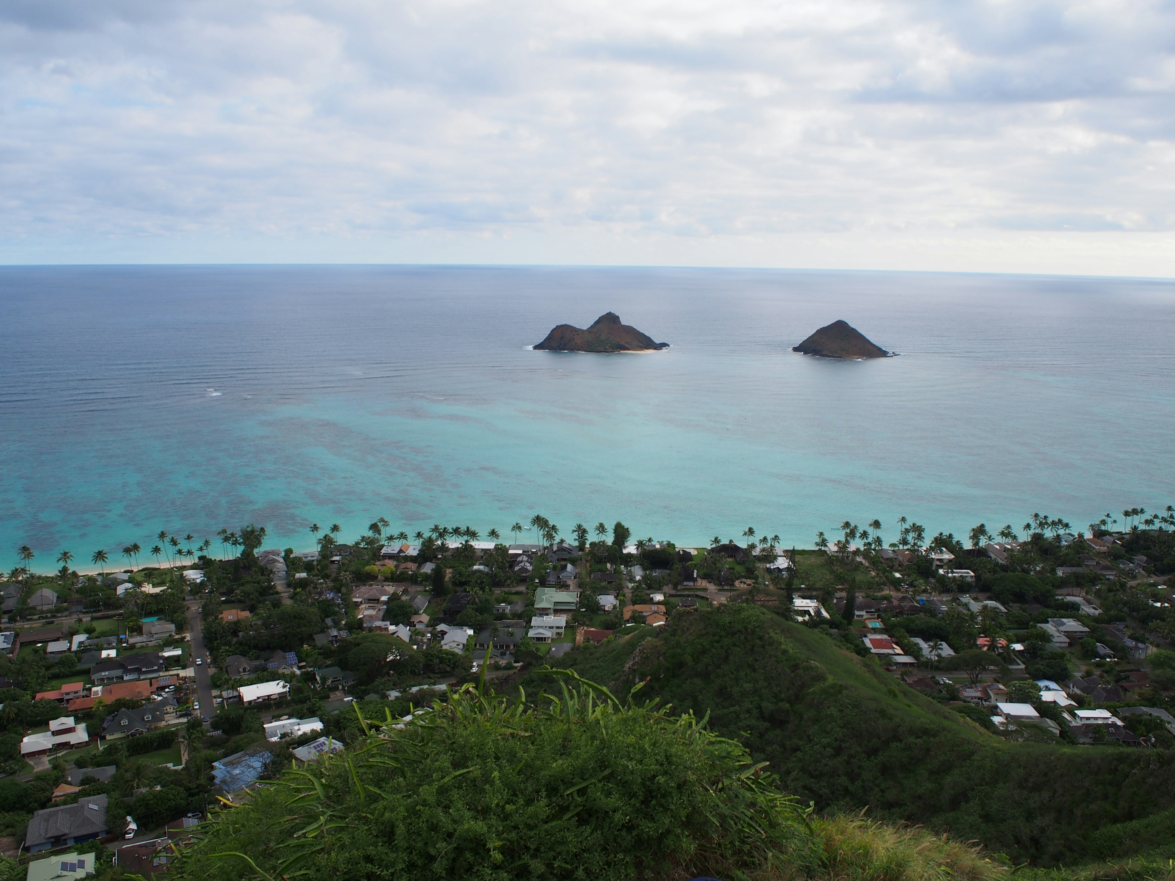 Pemandangan Hawaii dengan dua pulau kecil di lautan biru di bawah langit mendung