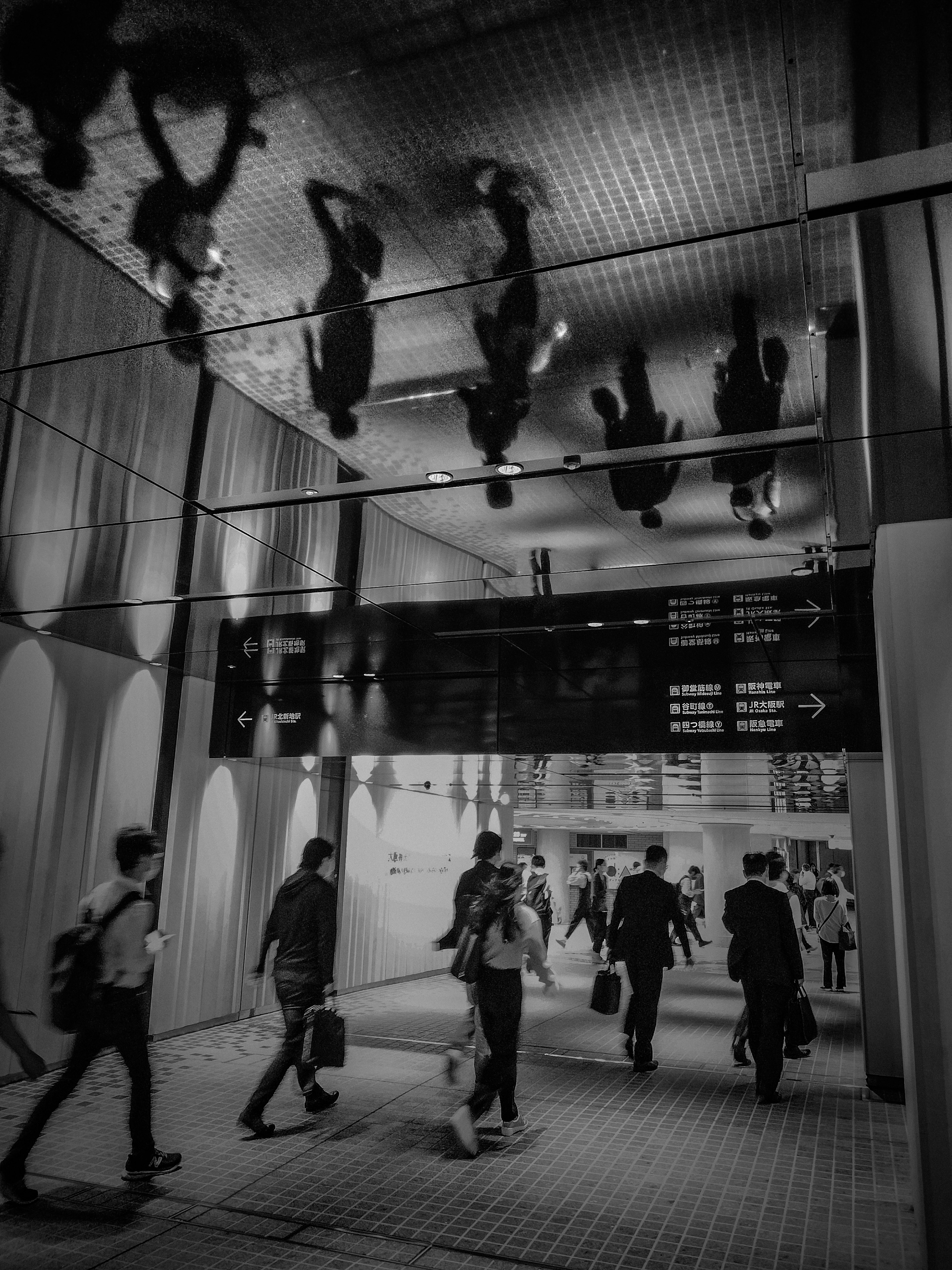 Scena di un corridoio di stazione moderna con riflessi di persone che camminano