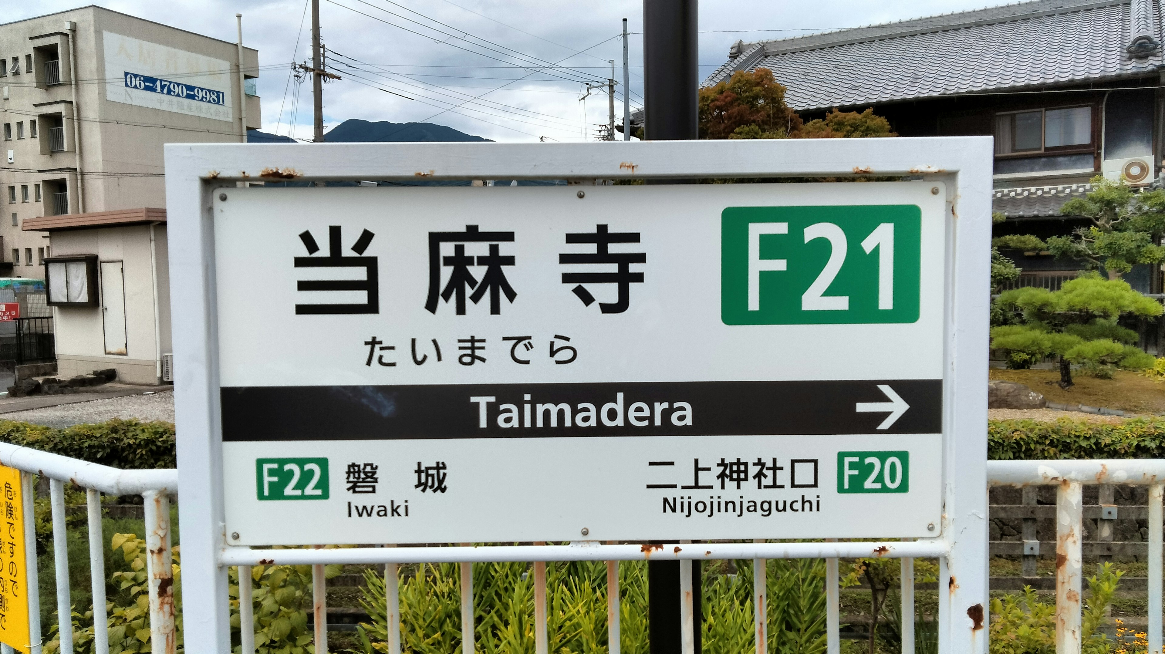 Insegna della stazione Taimadera che mostra F21 e paesaggio circostante