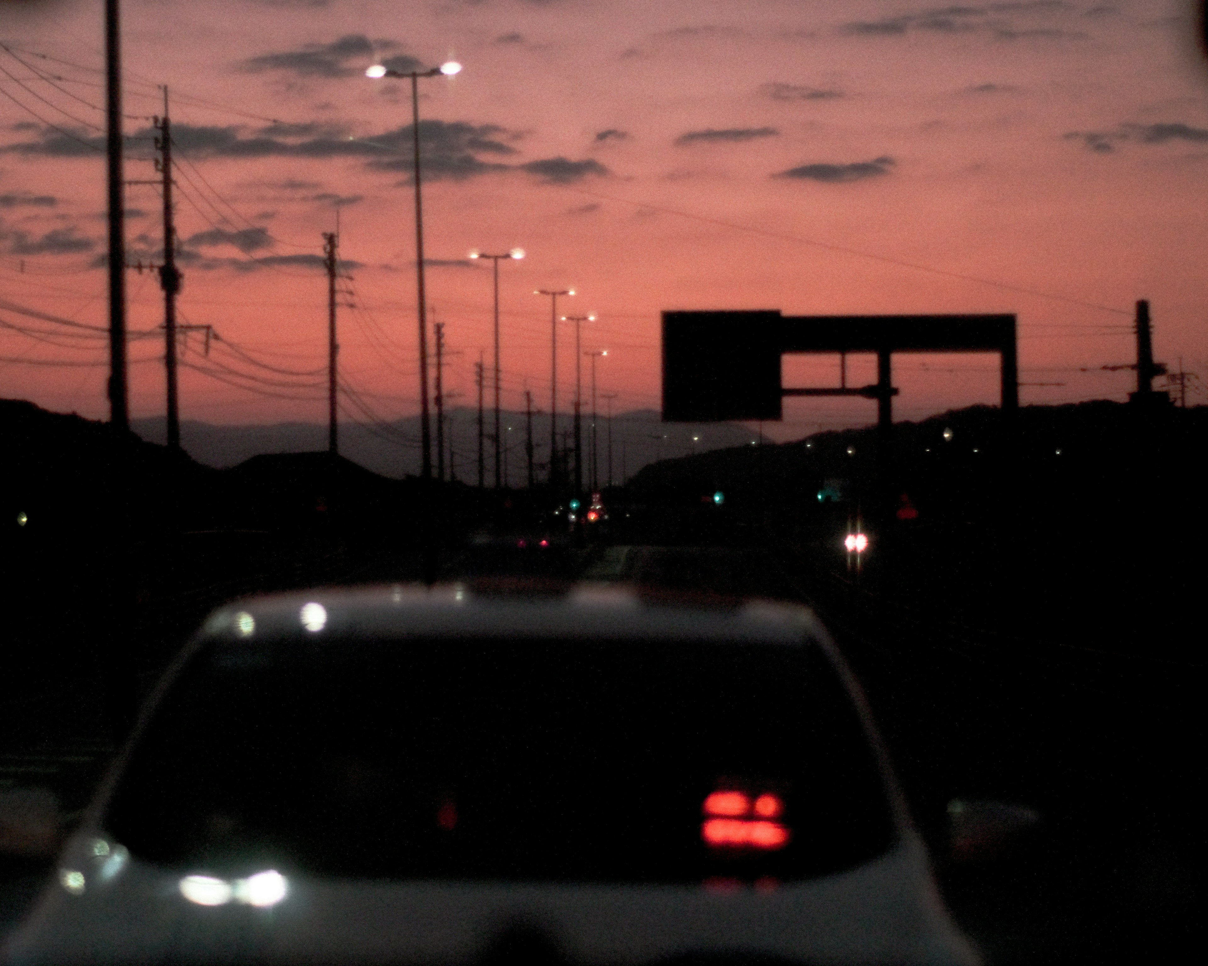 Escena de carretera con farolas y cielo al atardecer