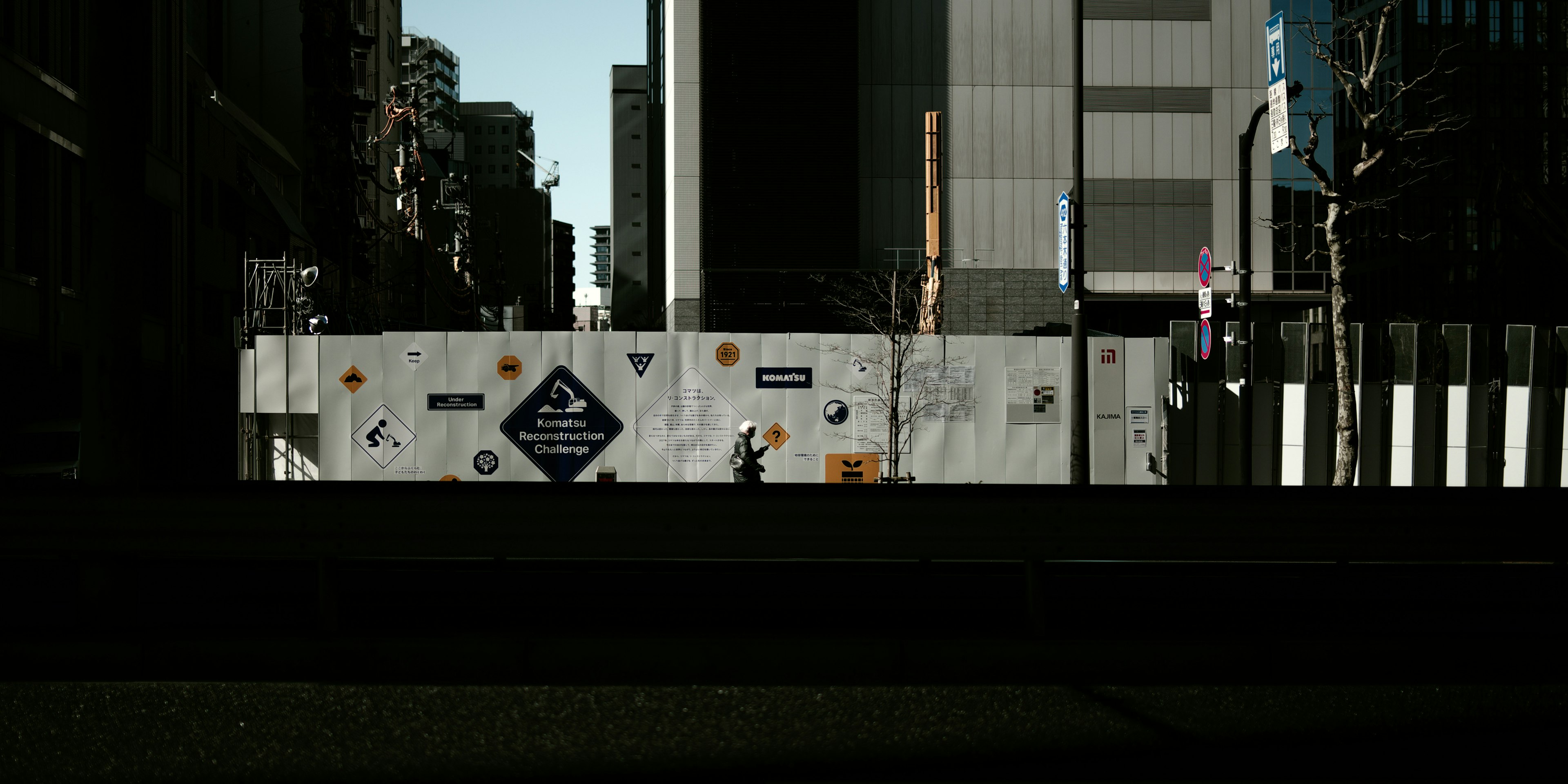 Chantier de construction avec clôture blanche et personne en milieu urbain