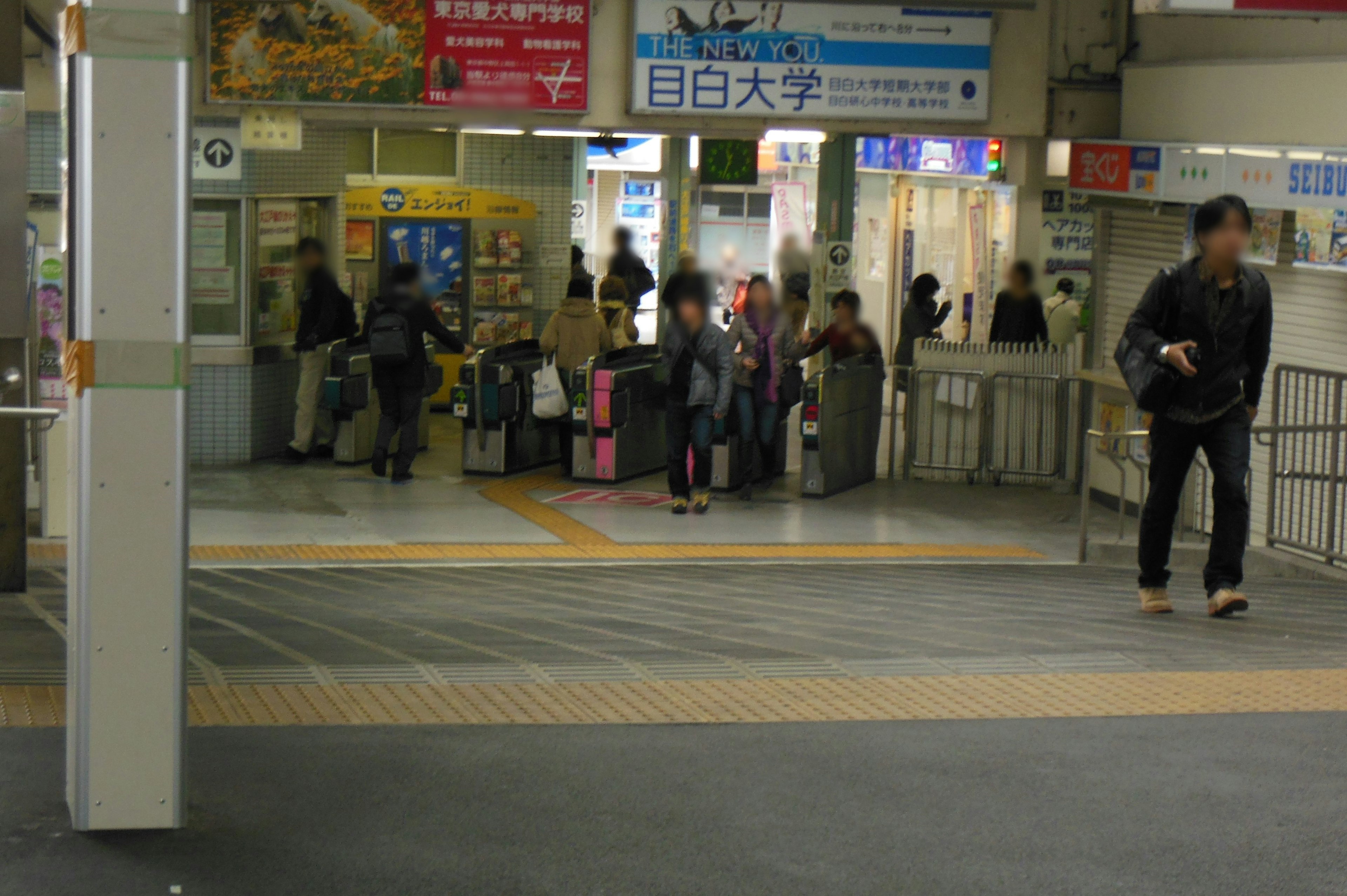 People waiting at the train station entrance with luggage