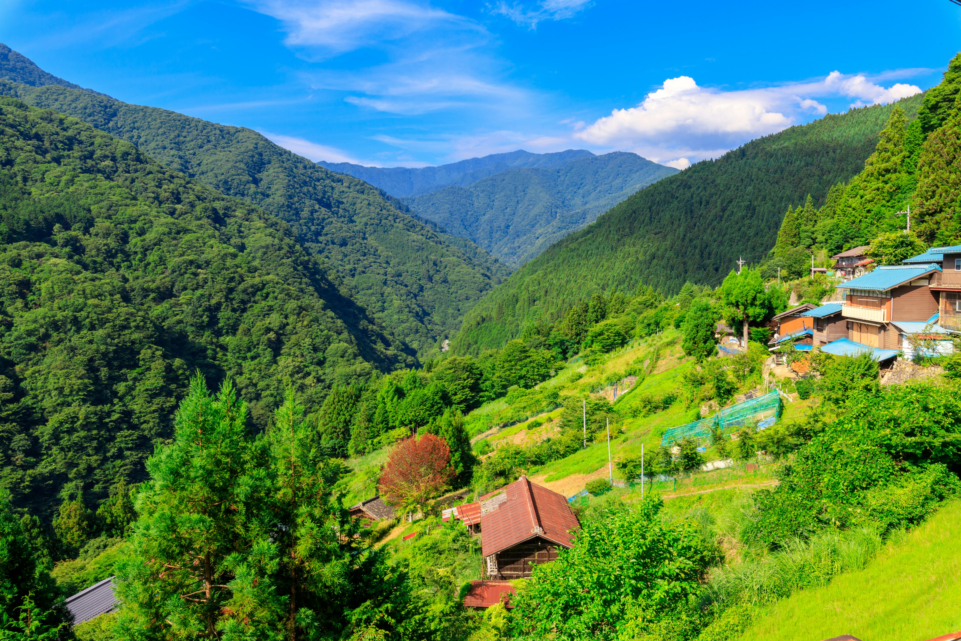 Paisaje de un pintoresco pueblo de montaña rodeado de colinas verdes con cielo azul y nubes blancas