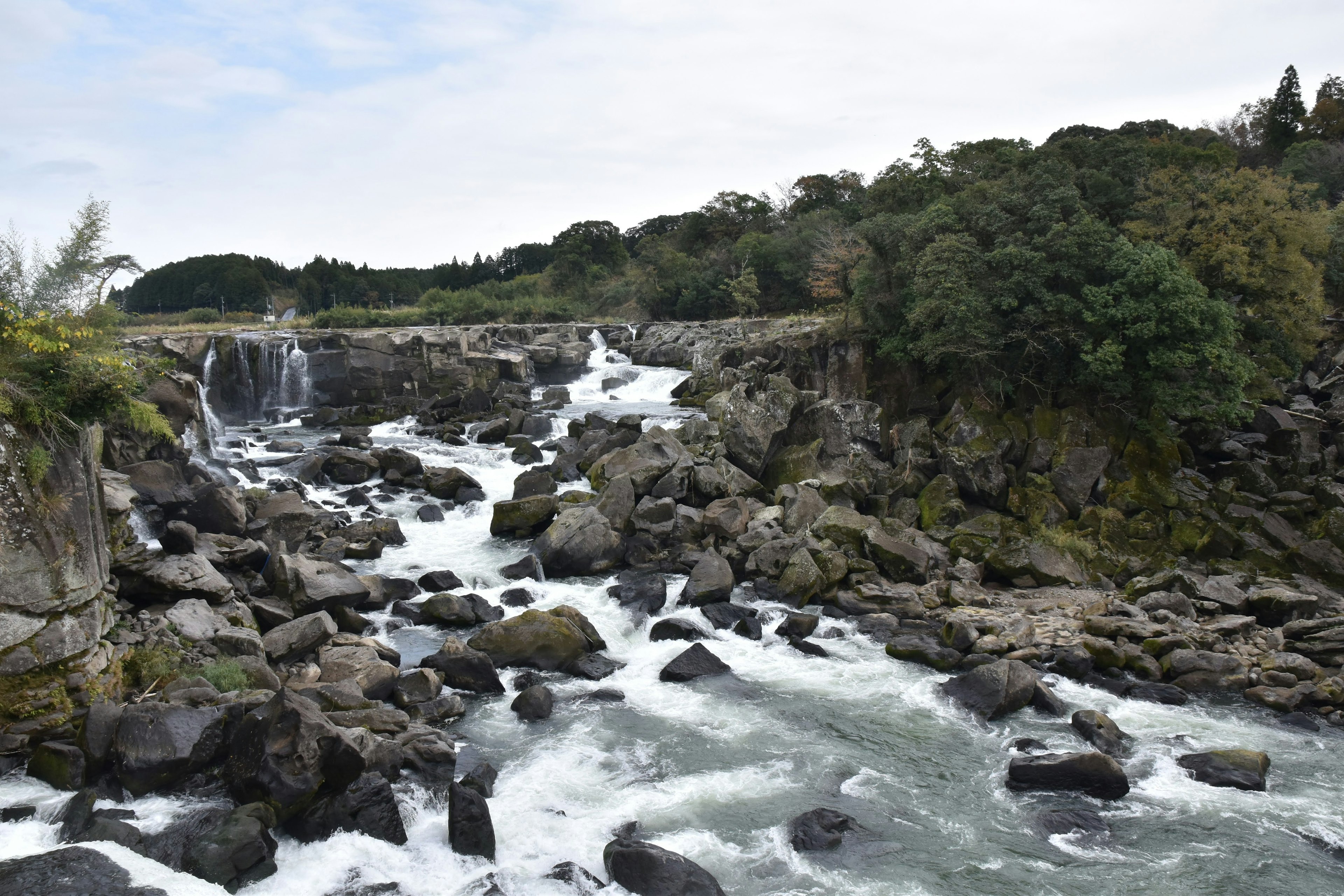 Vista panoramica di una cascata che scorre su rocce con vegetazione lussureggiante