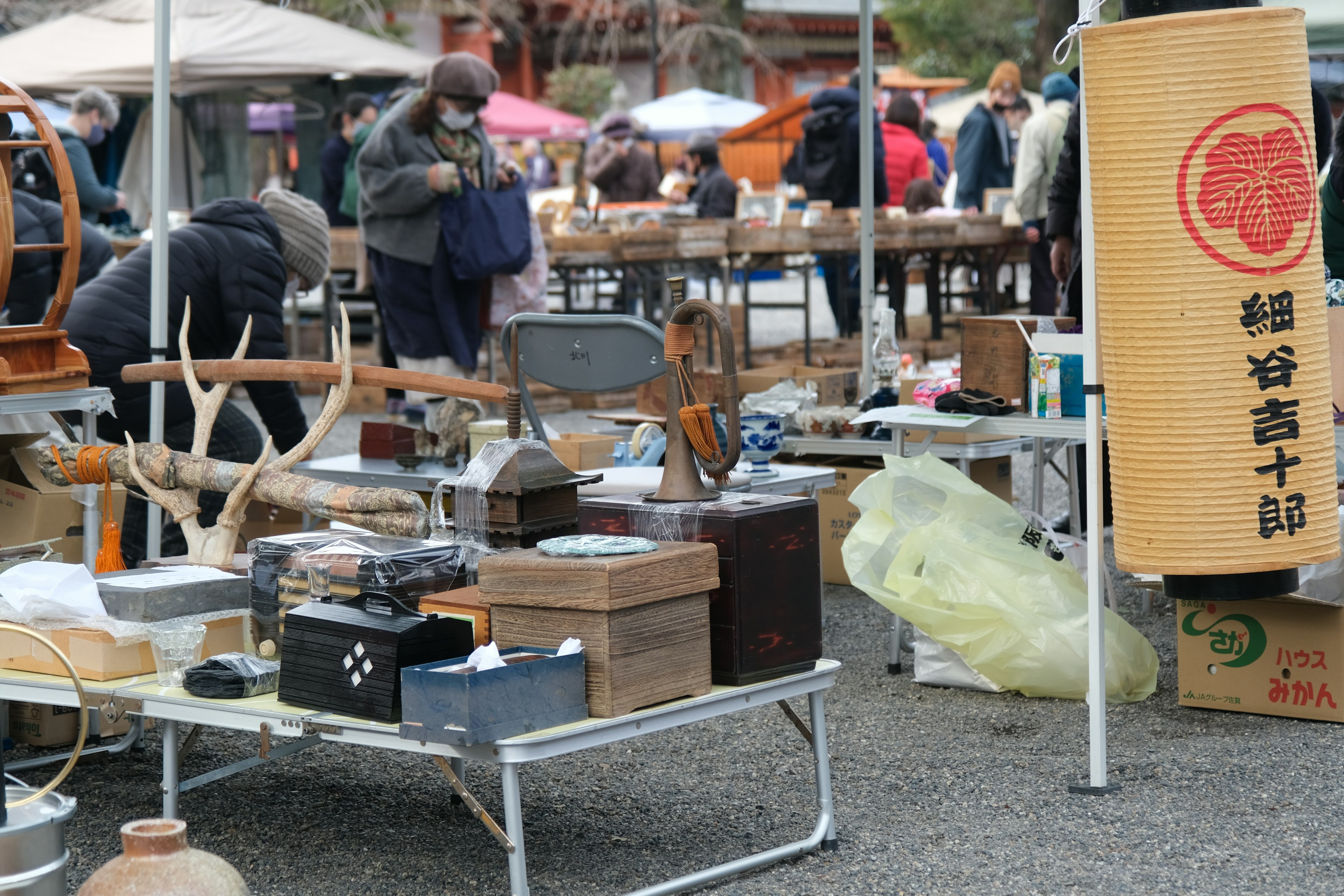 骨董品や雑貨が並ぶ市場の風景 人々が歩き回り物を見ている