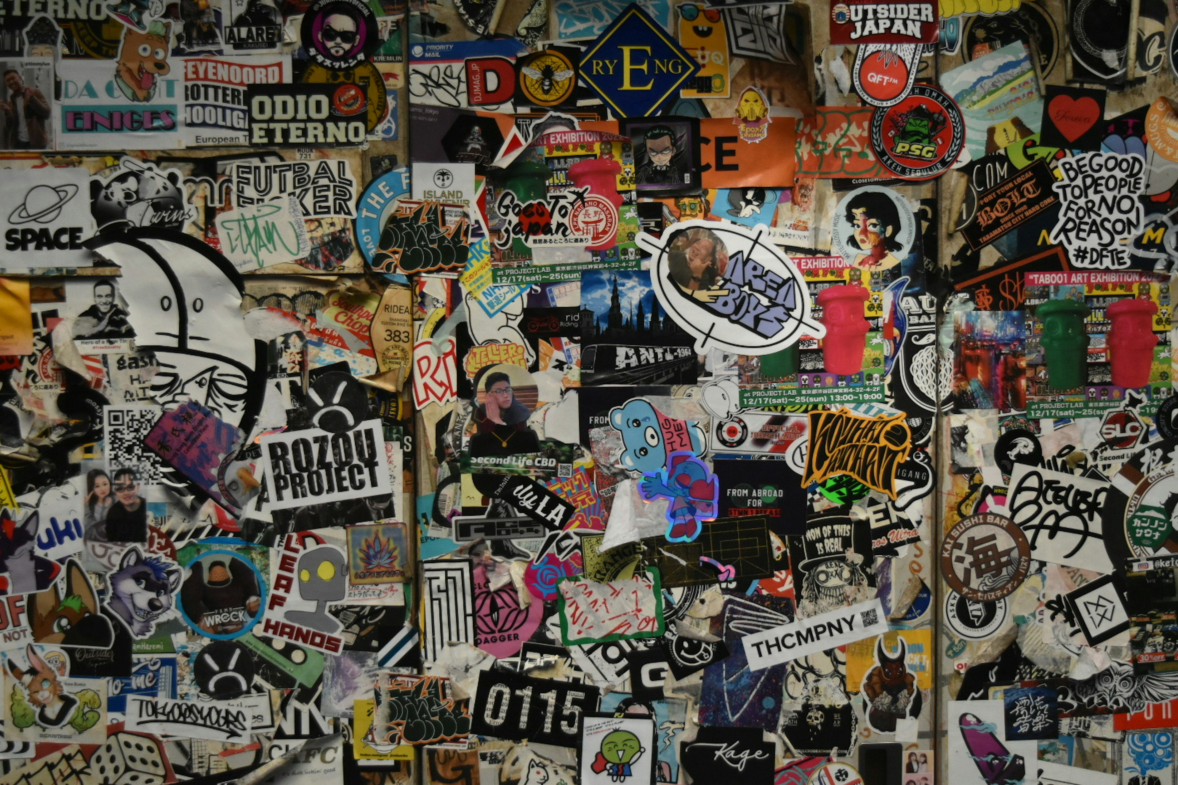 Una pared cubierta de varios stickers y graffiti