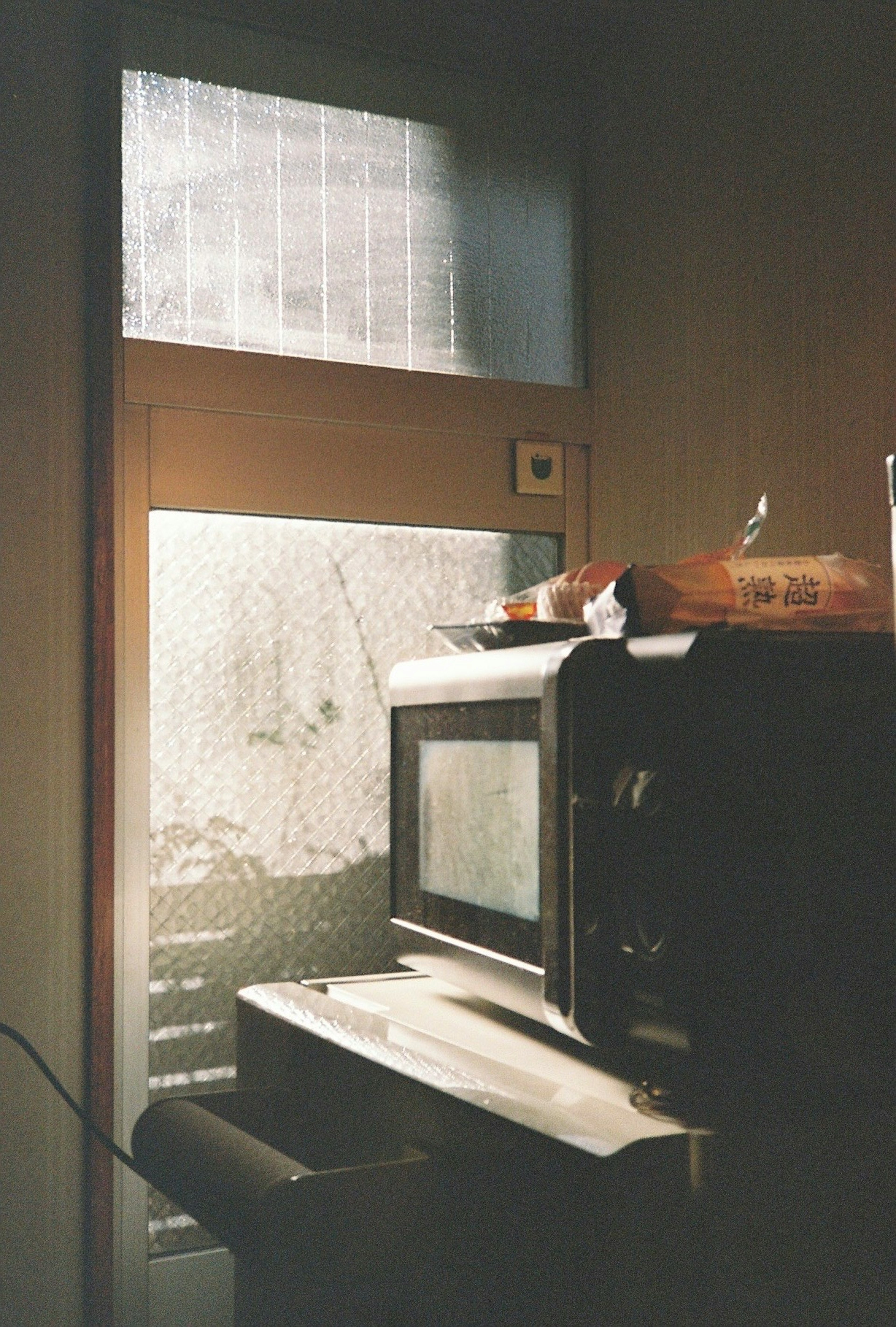 A kitchen scene showing a microwave on a counter with a foggy window in the background